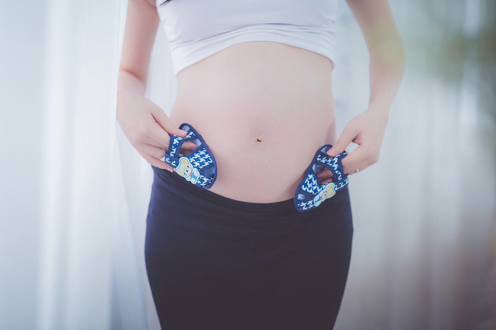 Femme enceinte tenant des chaussures de bébé. | Source : Pexels