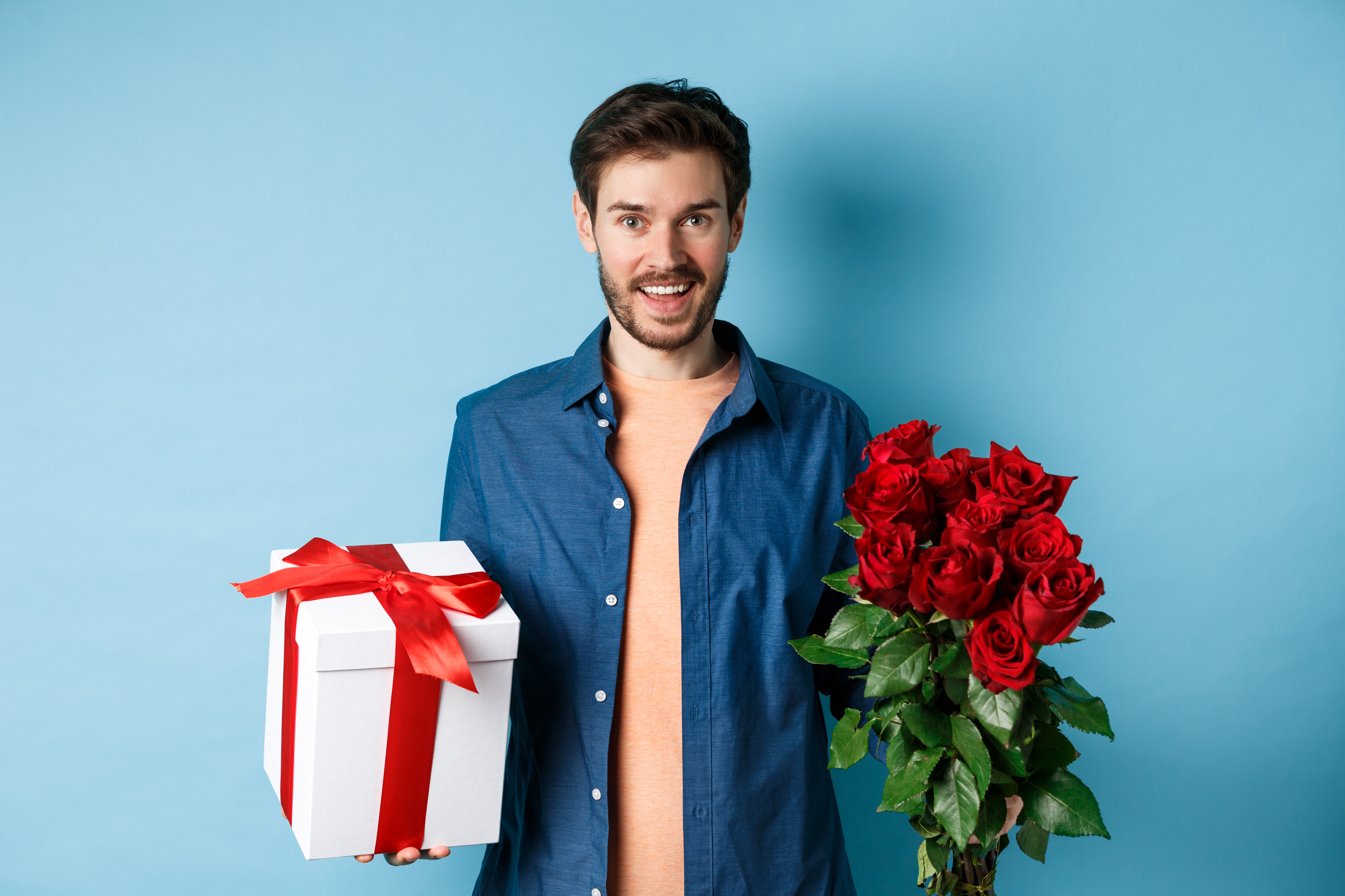 Homme tenant un bouquet de roses et un paquet cadeau | Source : Shutterstock