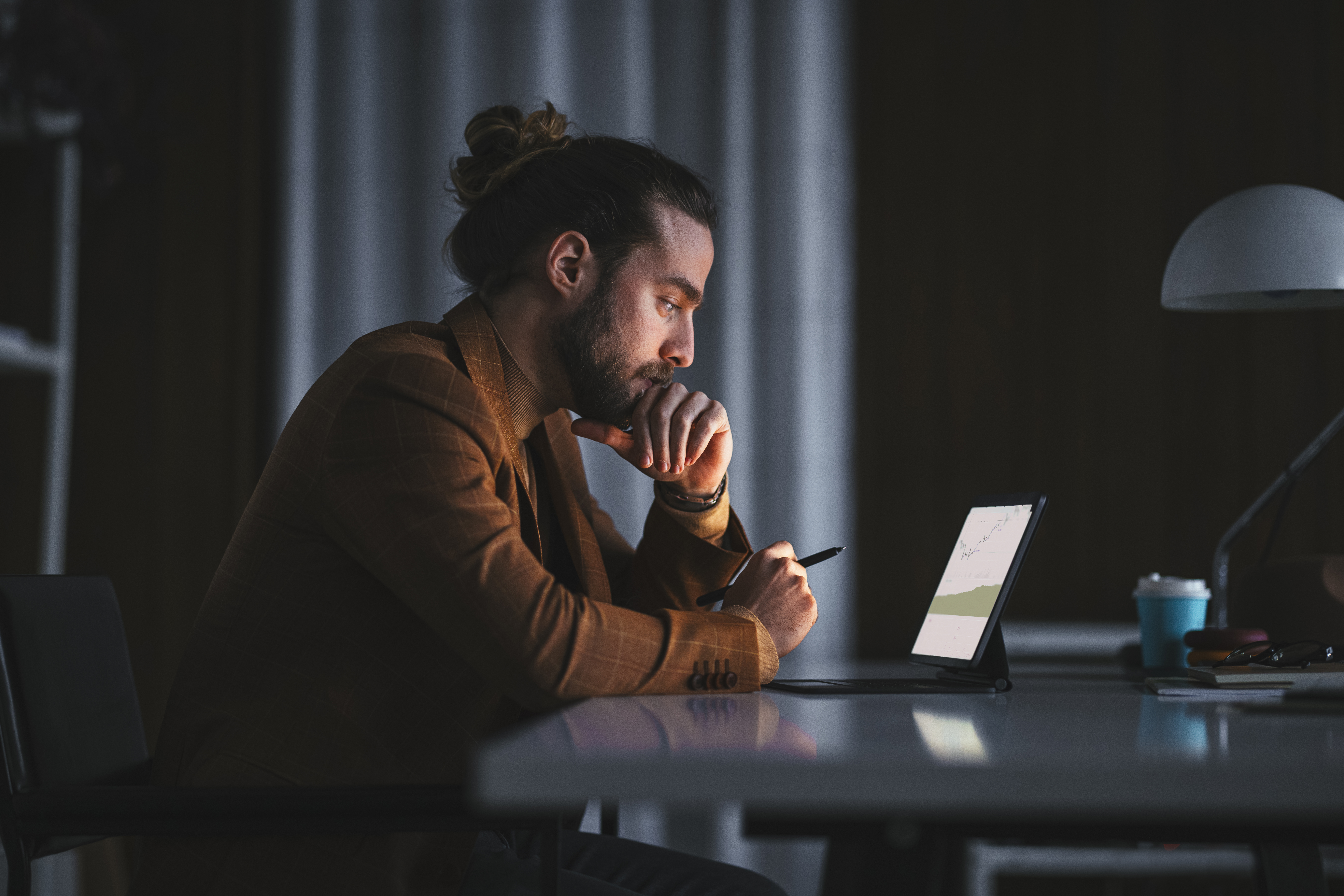 Homme pensif travaillant sur un ordinateur portable dans un bureau | Source : Getty Images