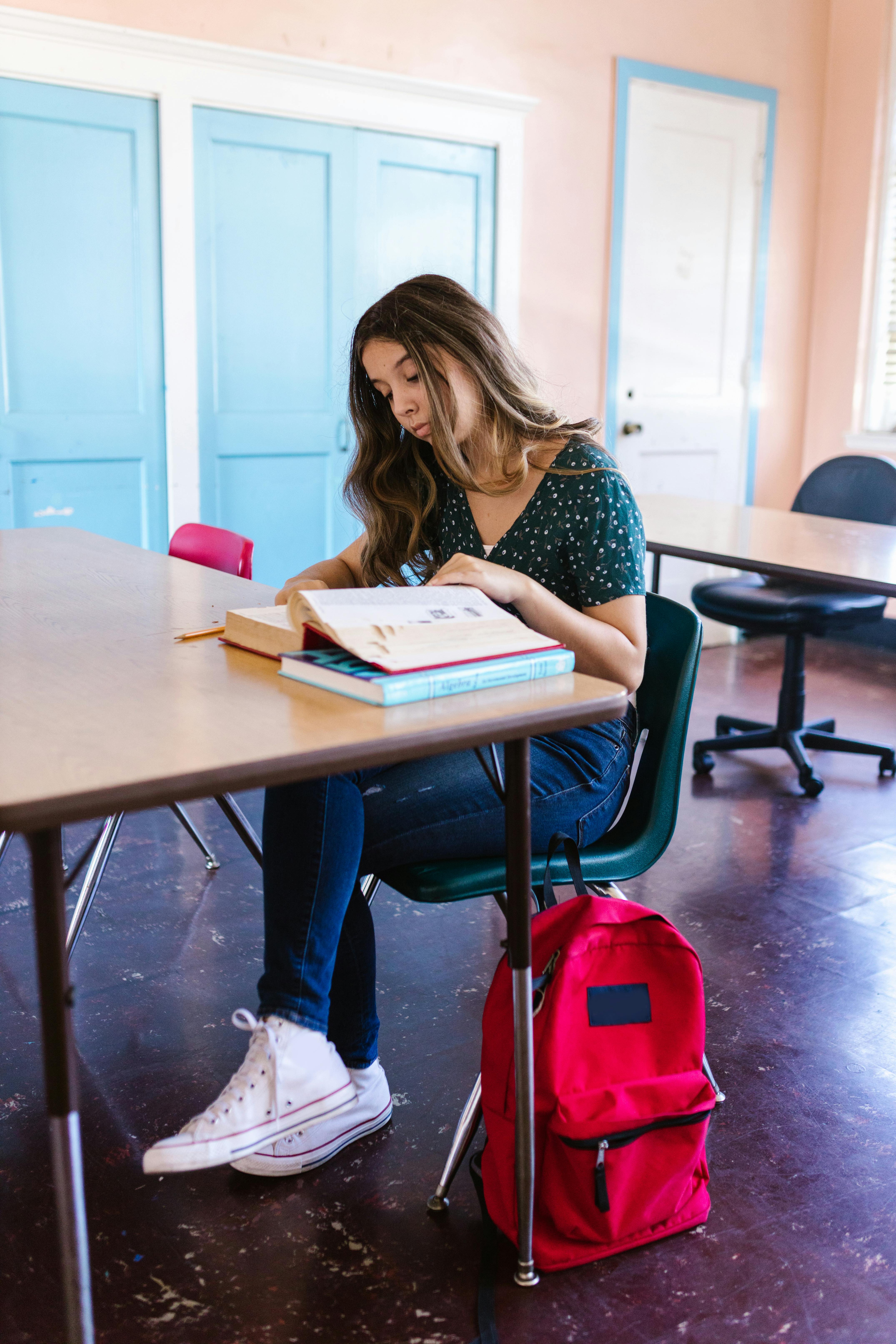 Une fille malheureuse assise à un bureau avec un livre devant elle à l'école | Source : Pexels