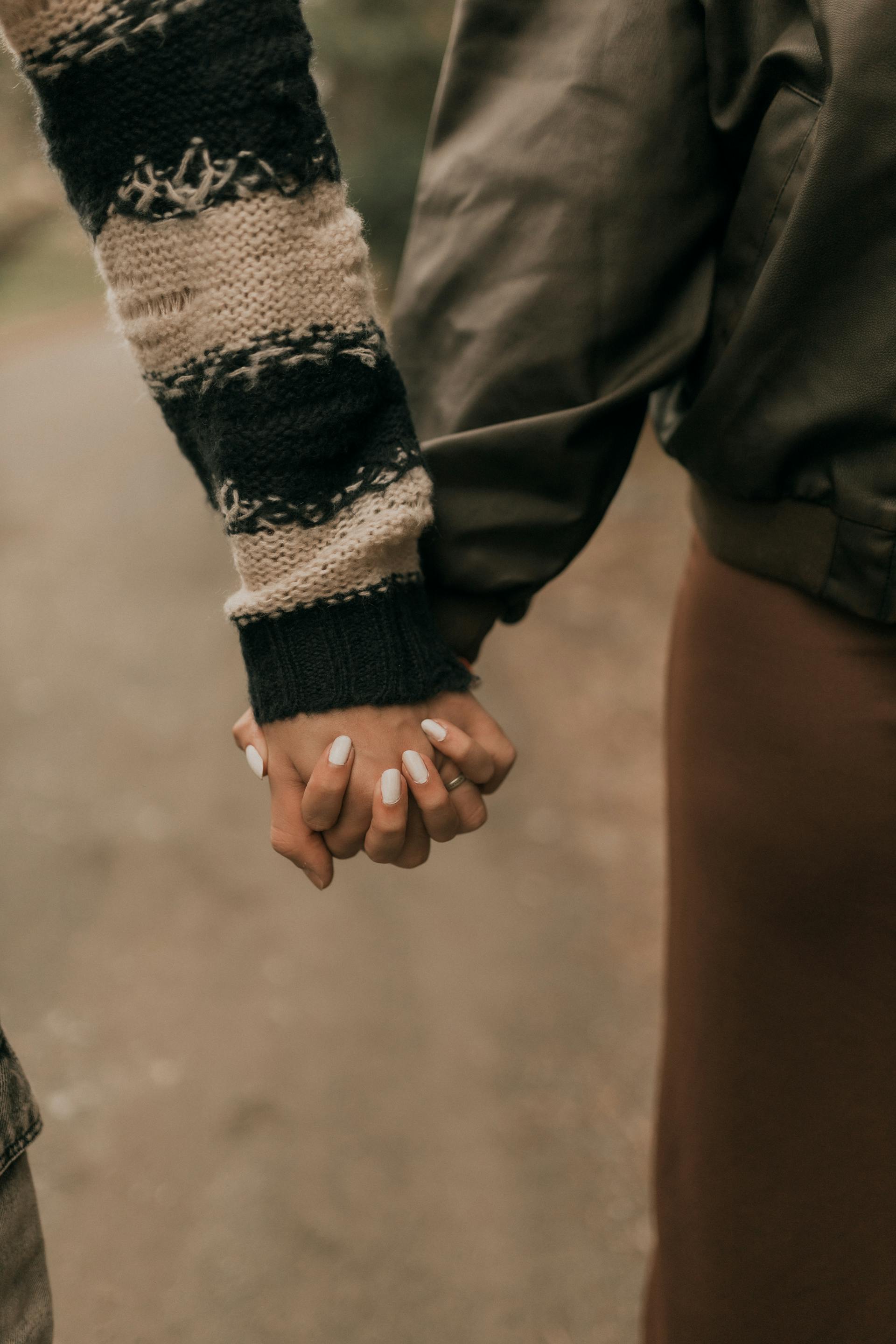 Gros plan d'un couple se tenant la main en plein air | Source : Pexels