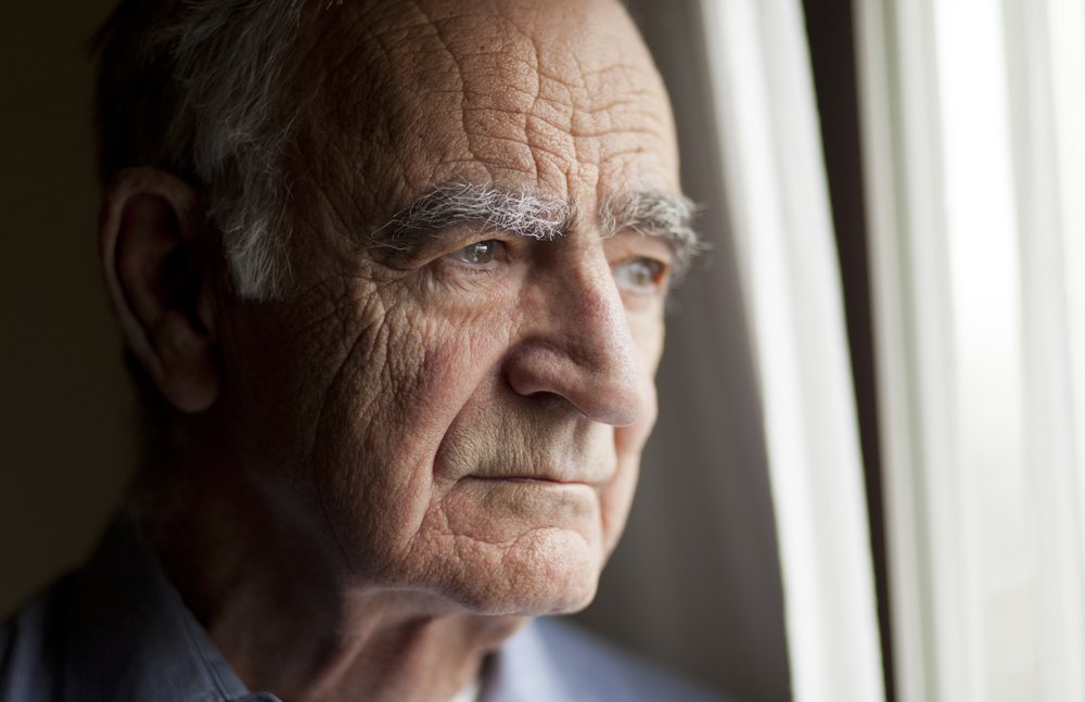 Un homme âgé regardant par la fenêtre. | Photo : Shutterstock