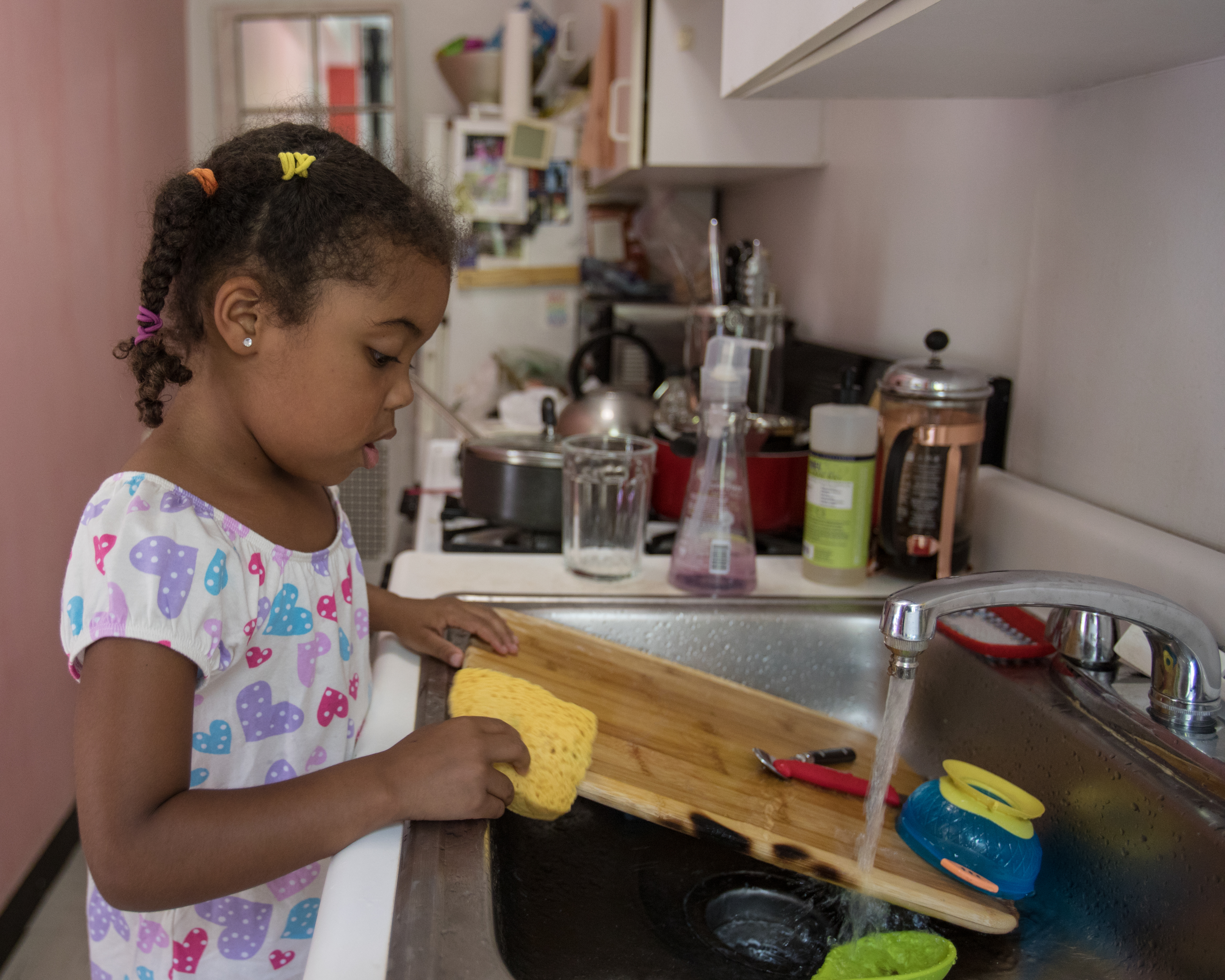 Une jeune fille lave la vaisselle dans une cuisine | Source : Getty Images