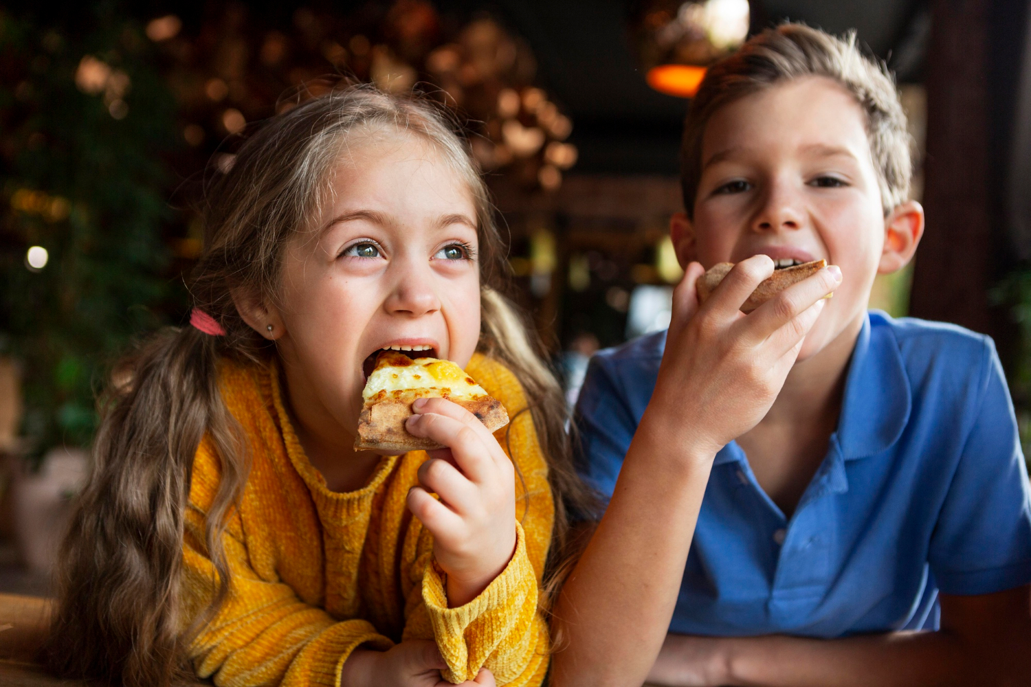 Des enfants excités qui mangent de la pizza | Source : Freepik