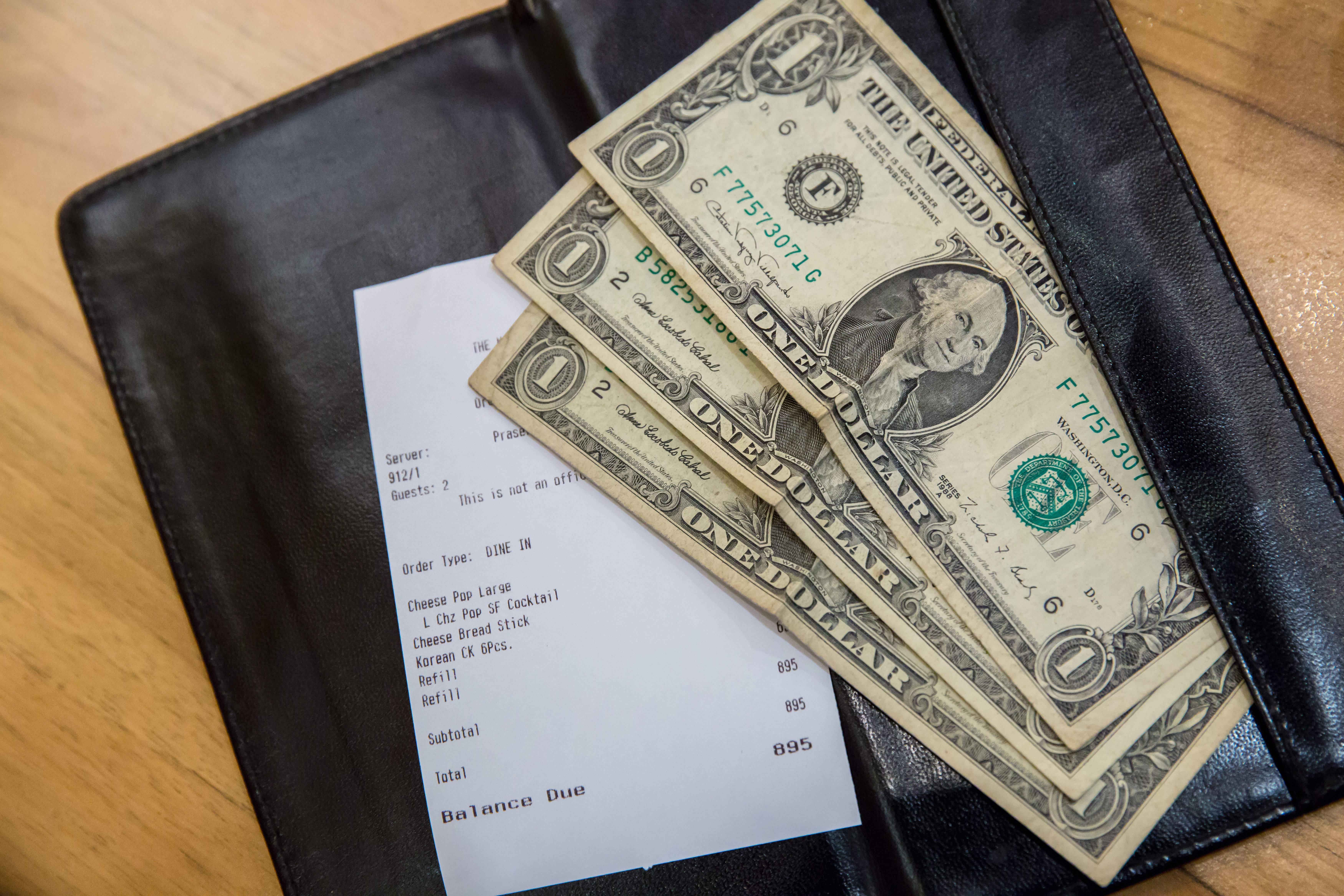 Une note de restaurant et quelques dollars. | Source : Shutterstock