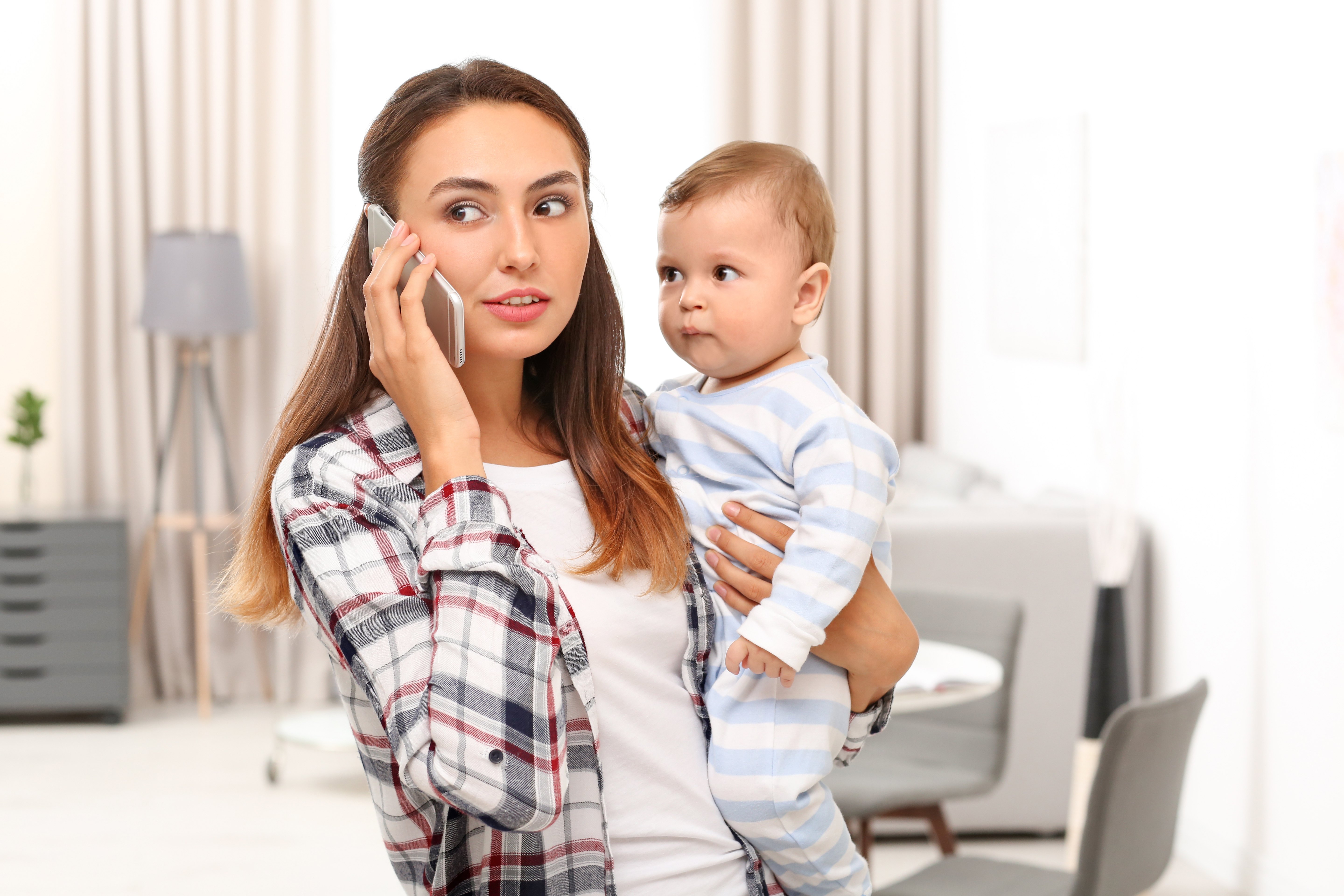 Une jeune mère tenant son bébé tout en parlant au téléphone | Source : Shutterstock