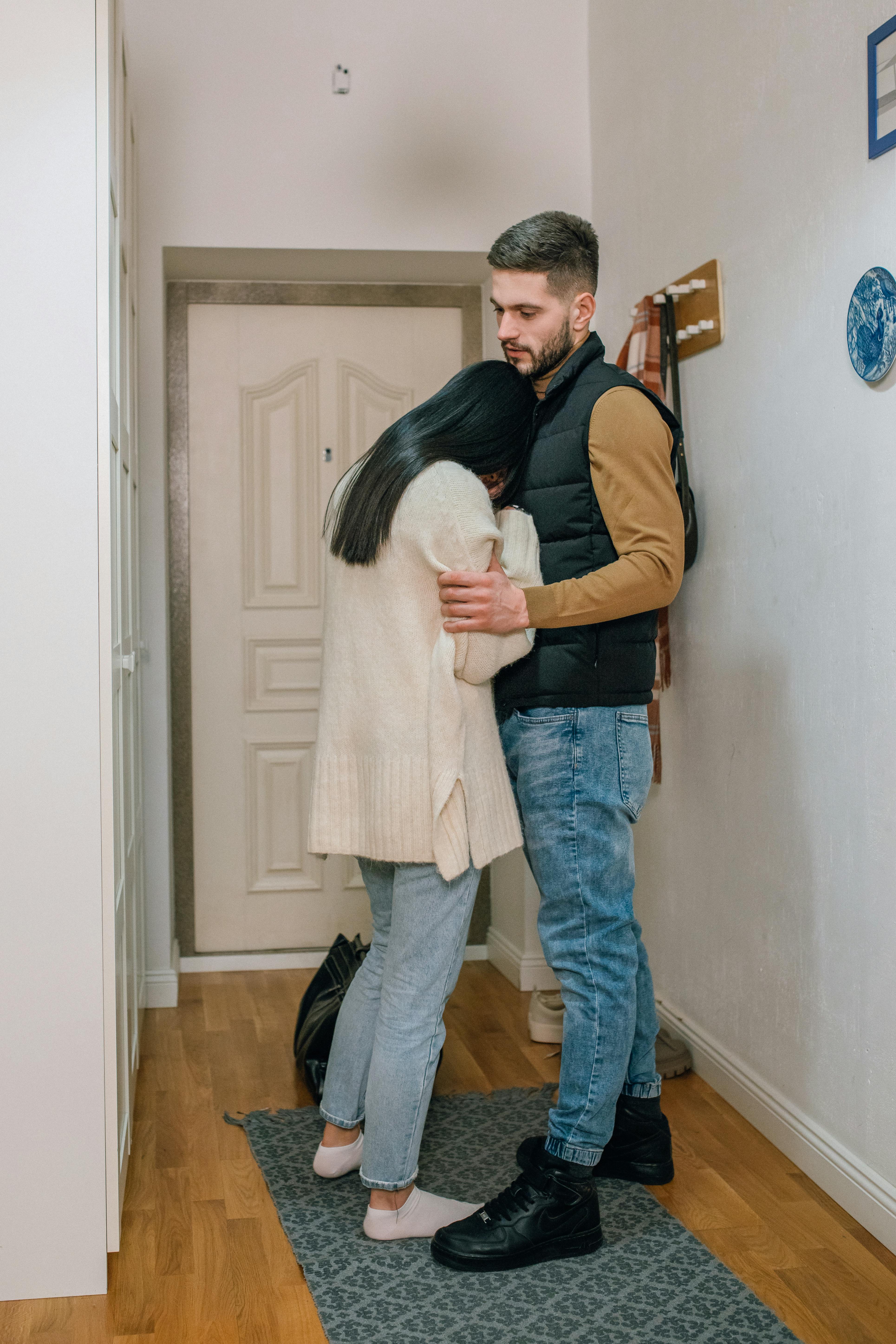 Un homme console une femme bouleversée à la porte d'entrée | Source : Pexels