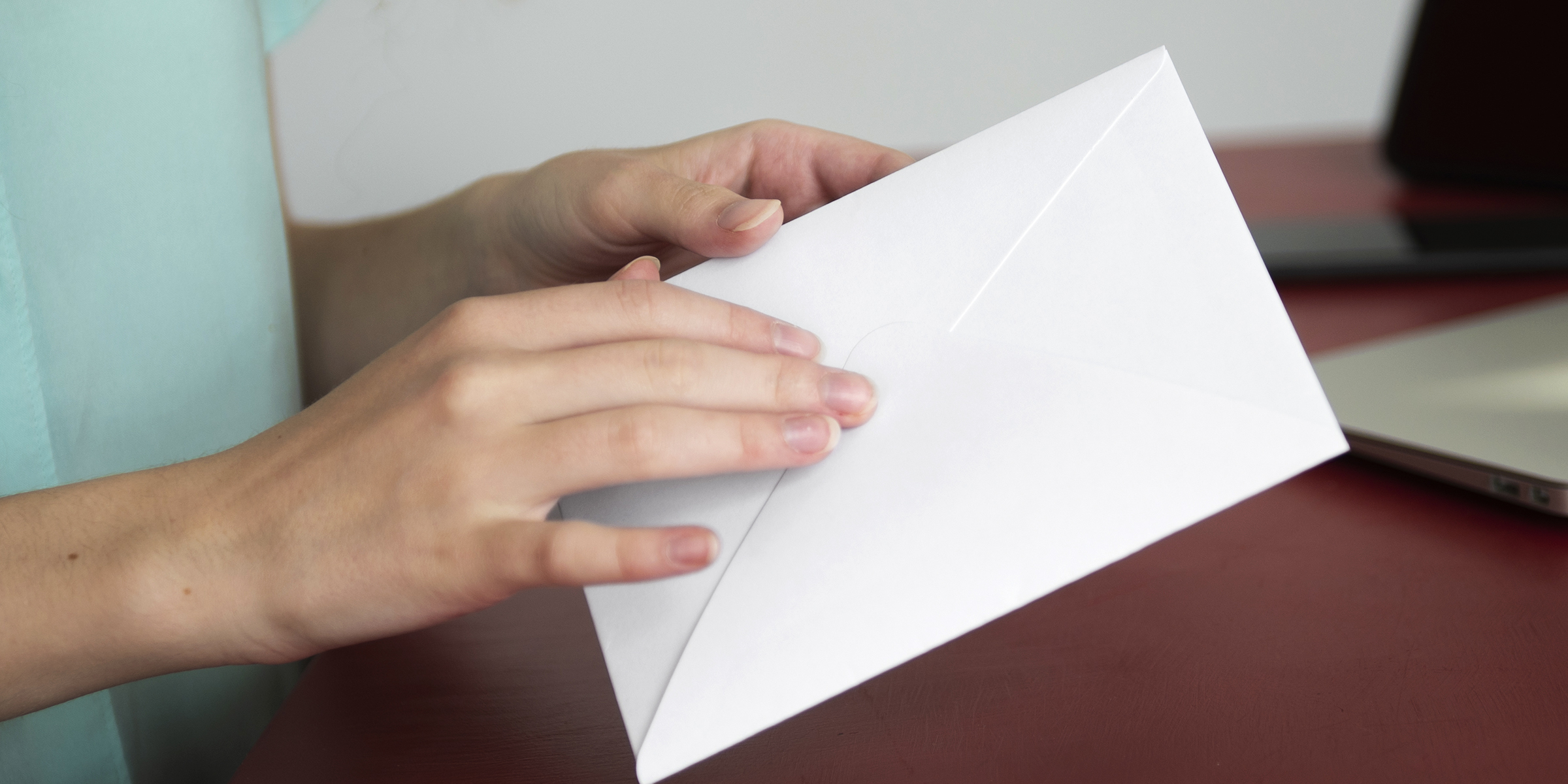 Une femme tenant une enveloppe blanche scellée | Source : Freepik