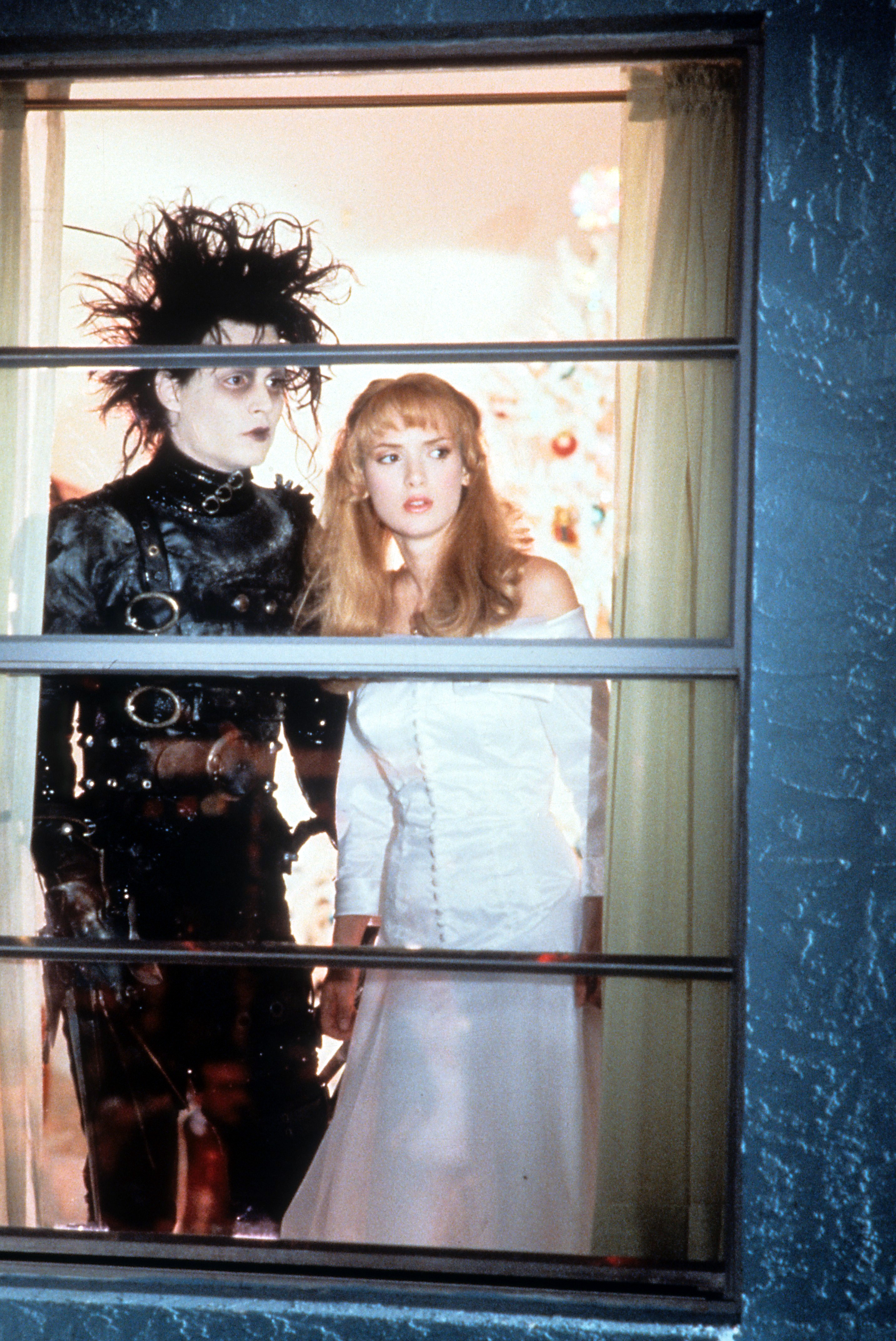 Johnny Depp et l'actrice Winona Ryder regardant par la fenêtre dans une scène du film "Edward Scissorhands", le 1er janvier 1990 | Source : Getty Images