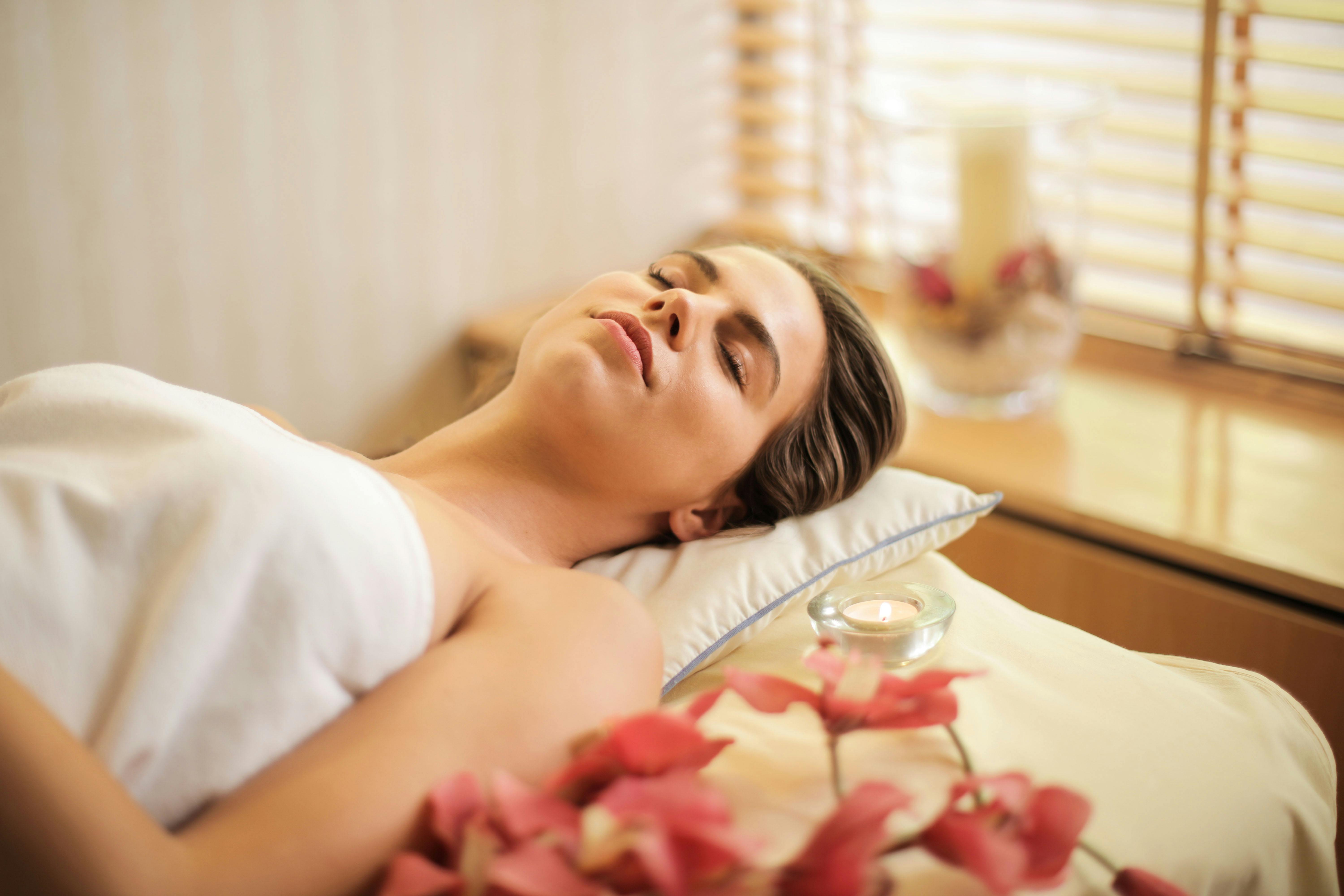 Une femme allongée sur un lit dans une serviette blanche | Source : Pexels