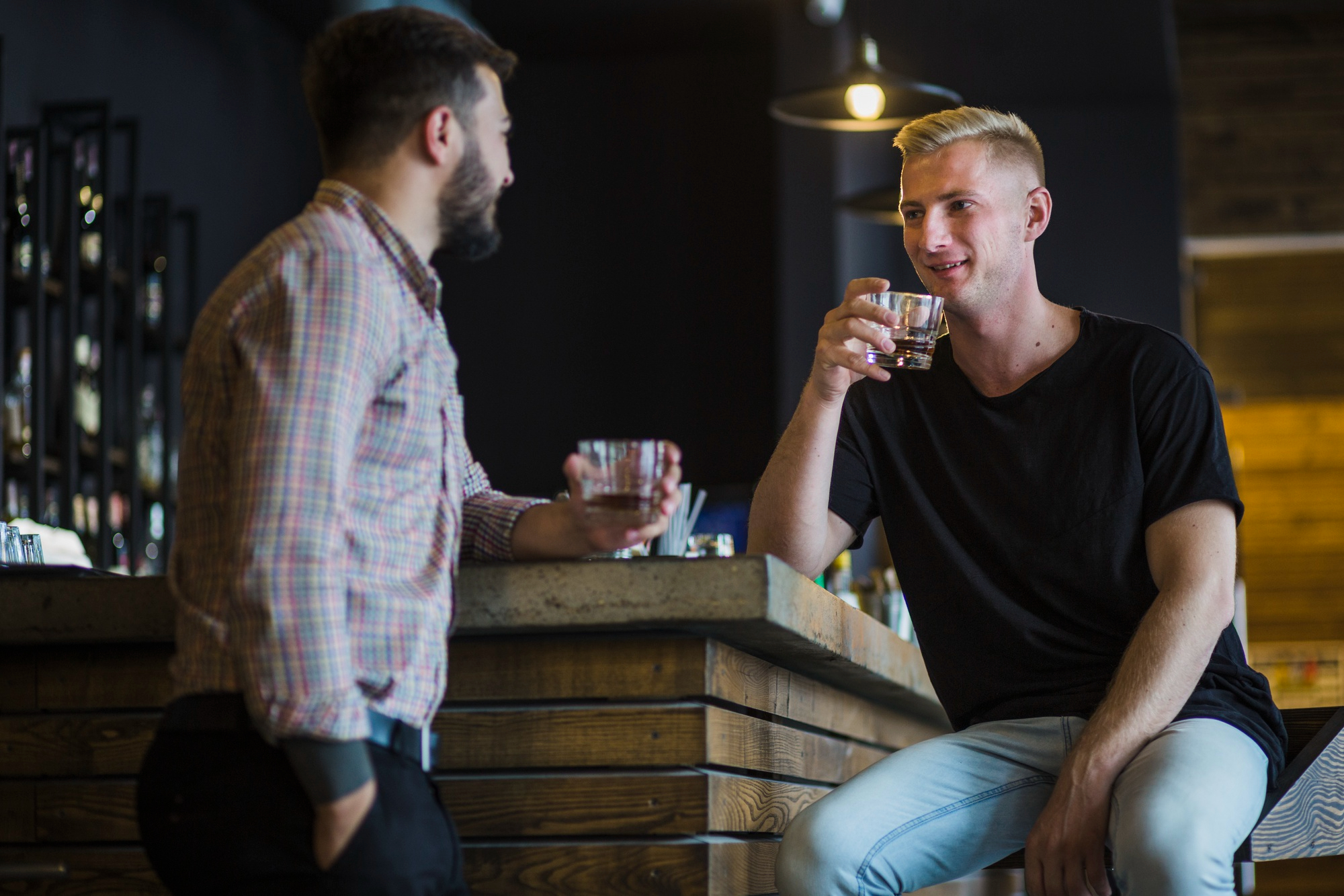 Deux amis masculins prenant un verre la nuit dans un bar | Source : Freepik