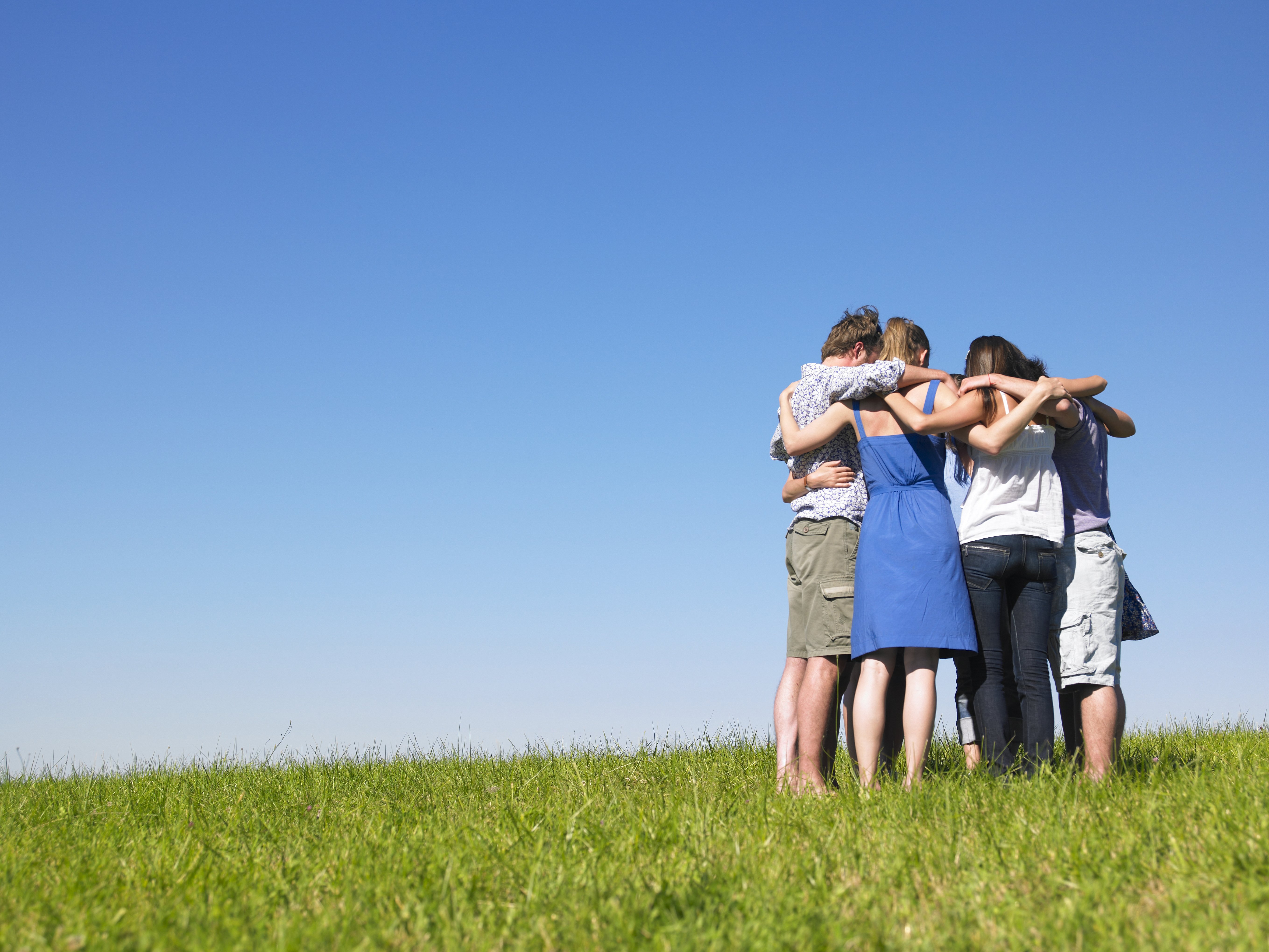 Un groupe de personnes s'embrassant dans un champ. │Source : Shutterstock