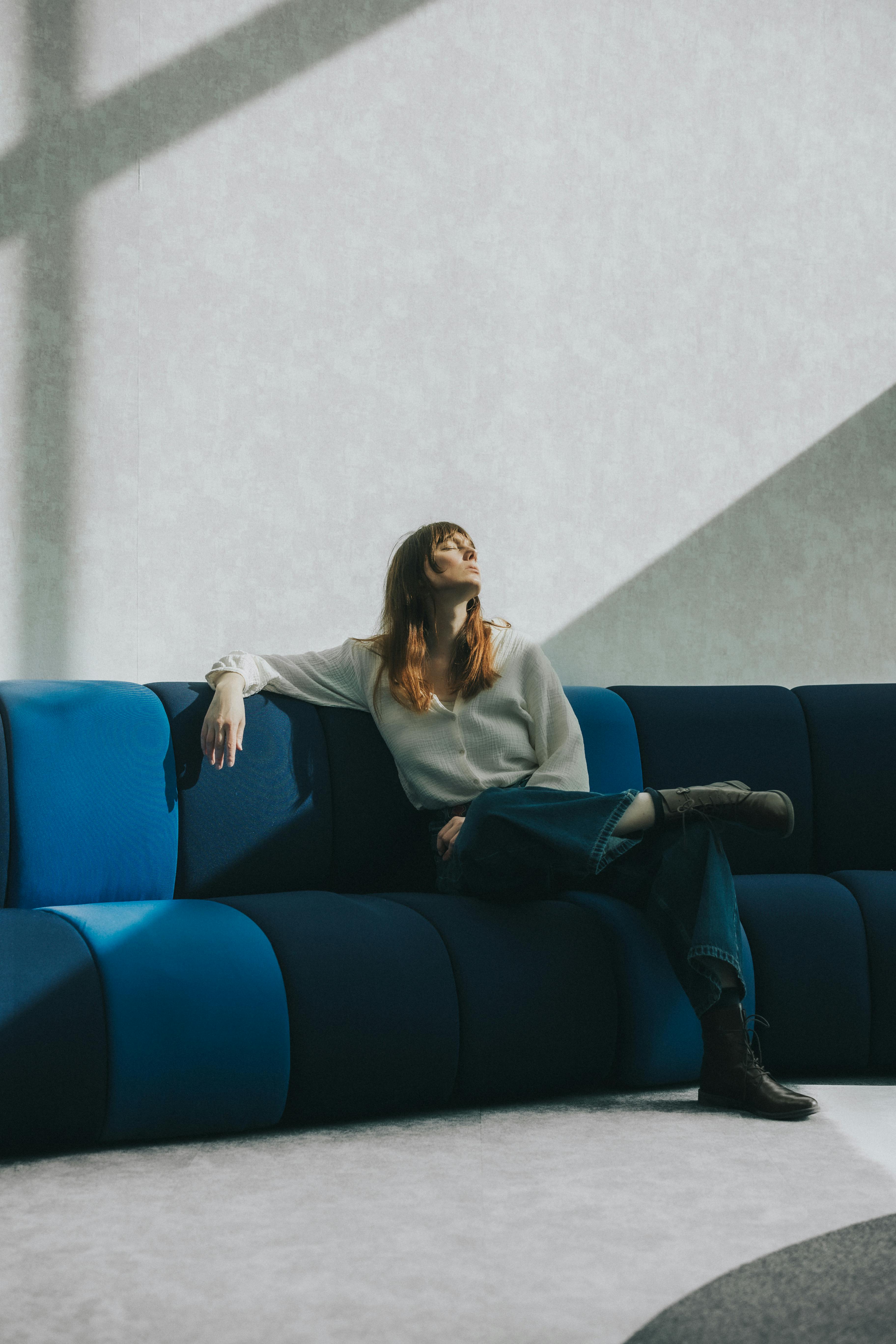 Une femme assise sur un canapé, plongée dans ses pensées | Source : Pexels