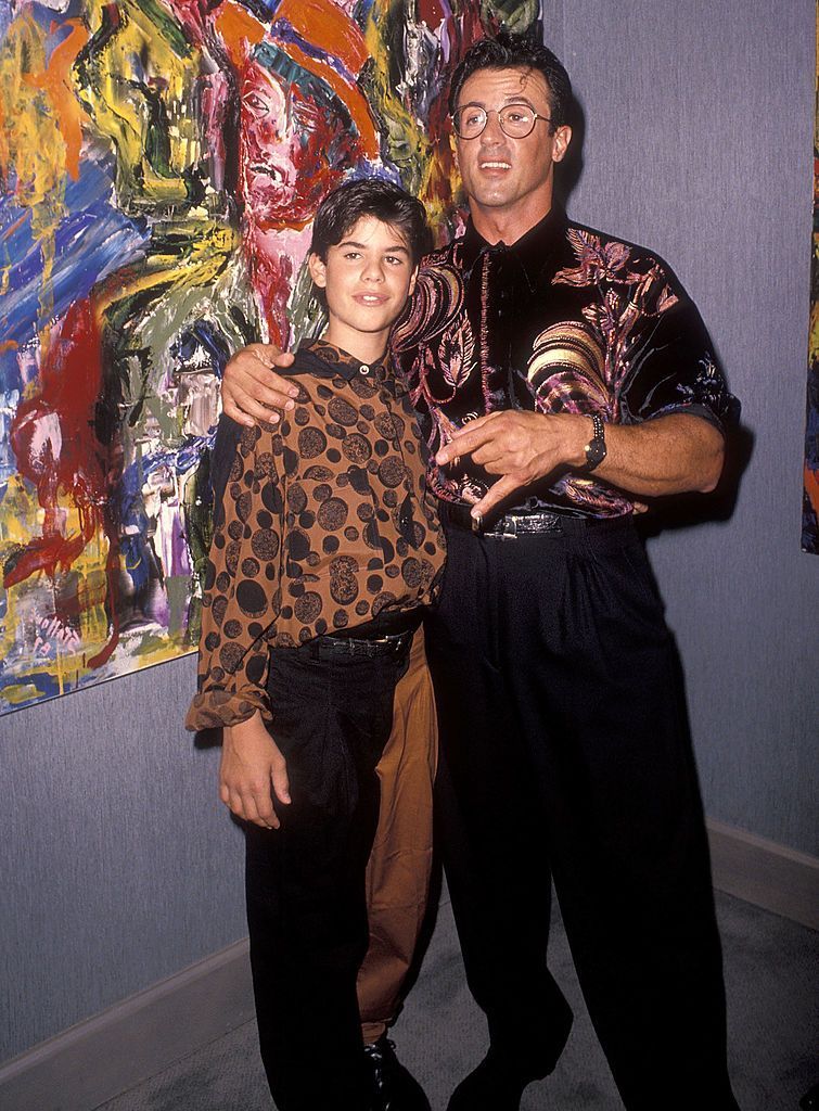 L'acteur Sylvester Stallone et son fils Sage lors de la soirée d'ouverture de l'exposition et du cocktail de Sylvester Stallone au profit de Yes on Proposition 128 "Big Green", le 10 septembre 1990 aux galeries Hanson à Beverly Hills, en Californie. | Source : Getty Images