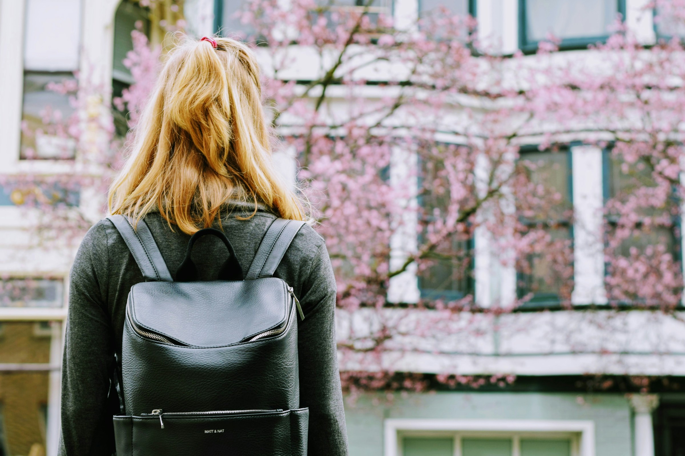 Vue arrière d'une jeune femme avec un sac à dos, debout devant un bâtiment | Source : Unsplash