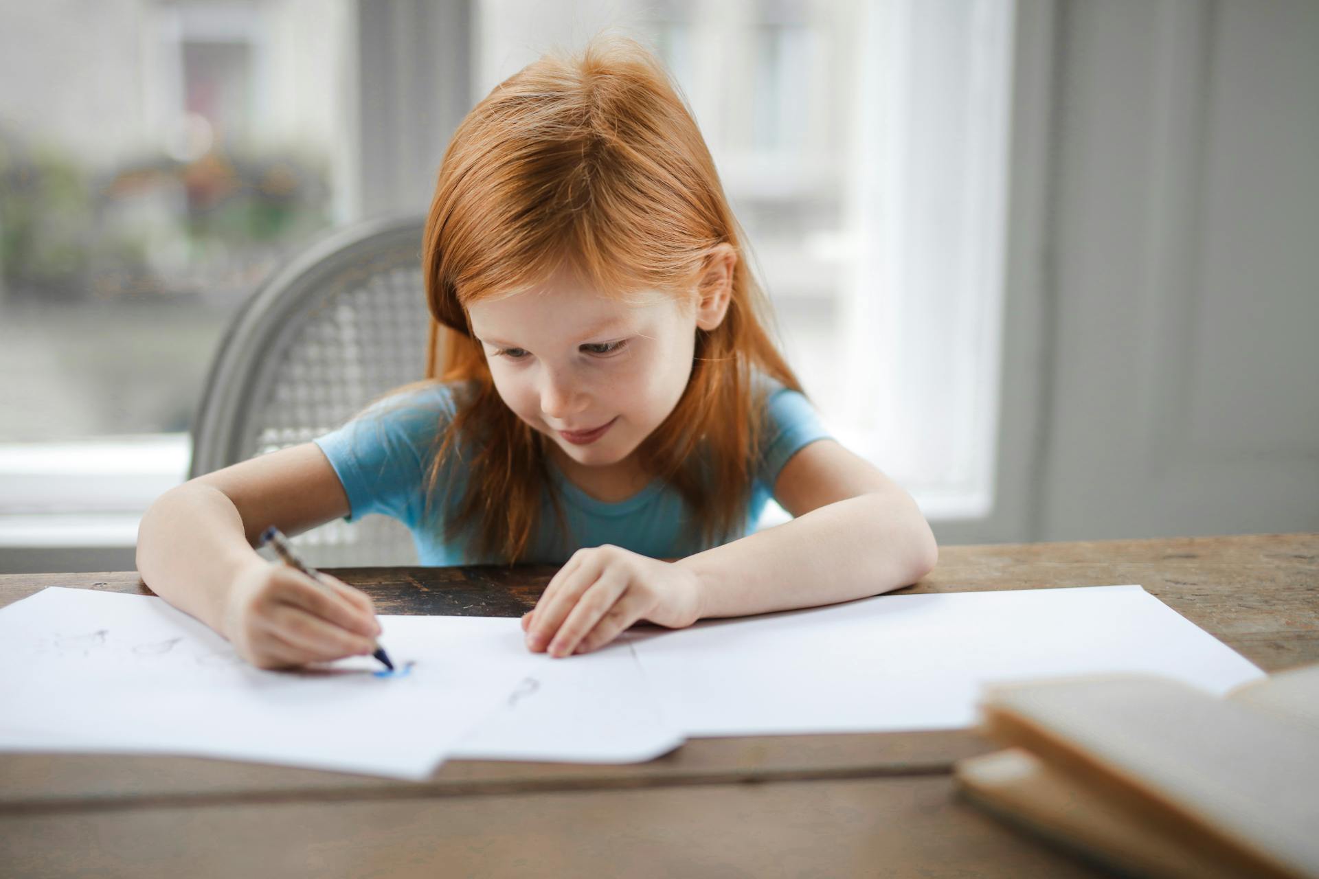 Un enfant assis à la table et qui fait du coloriage | Source : Pexels