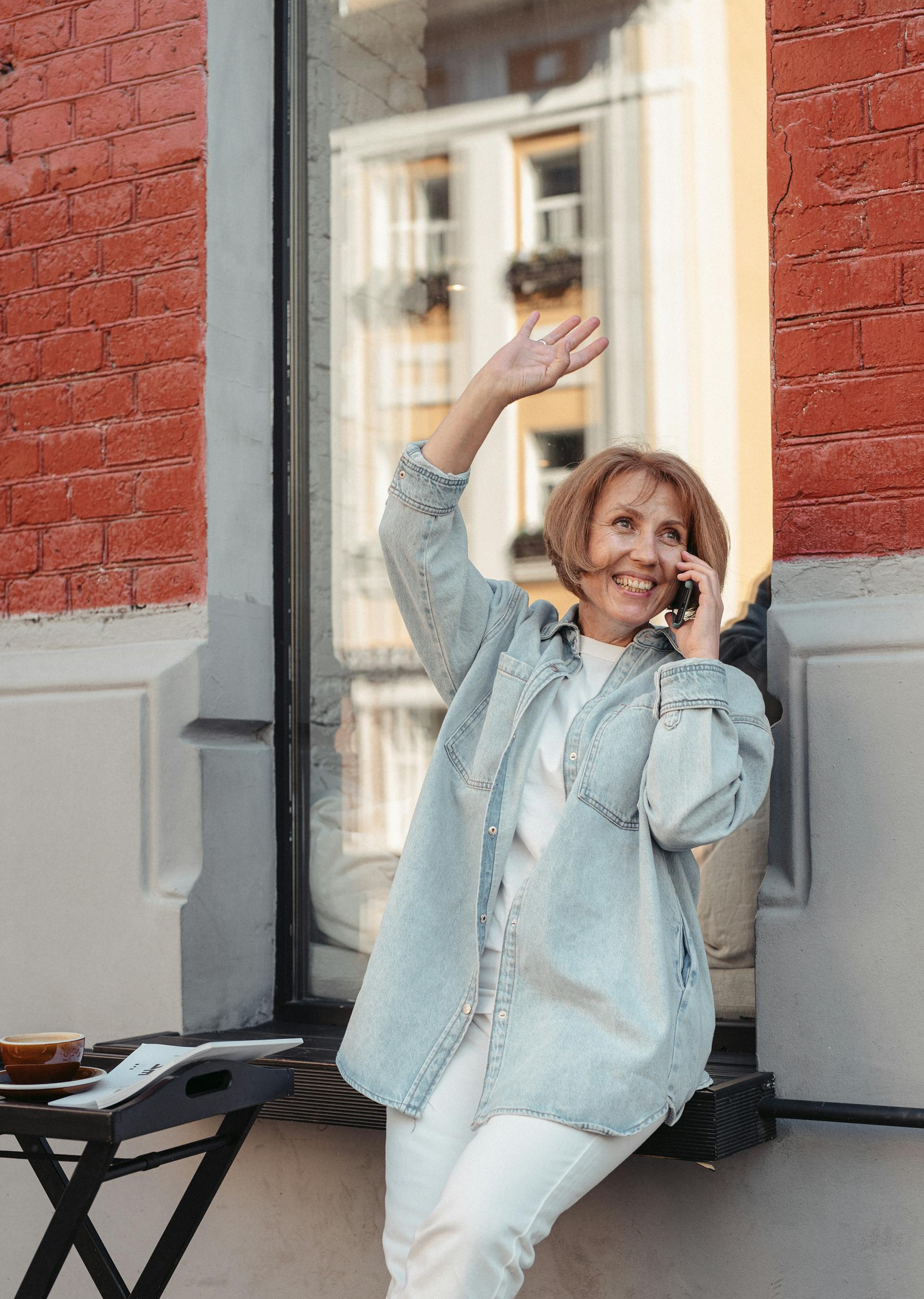 Une femme qui sourit et fait un signe de la main pendant un appel | Source : Pexels