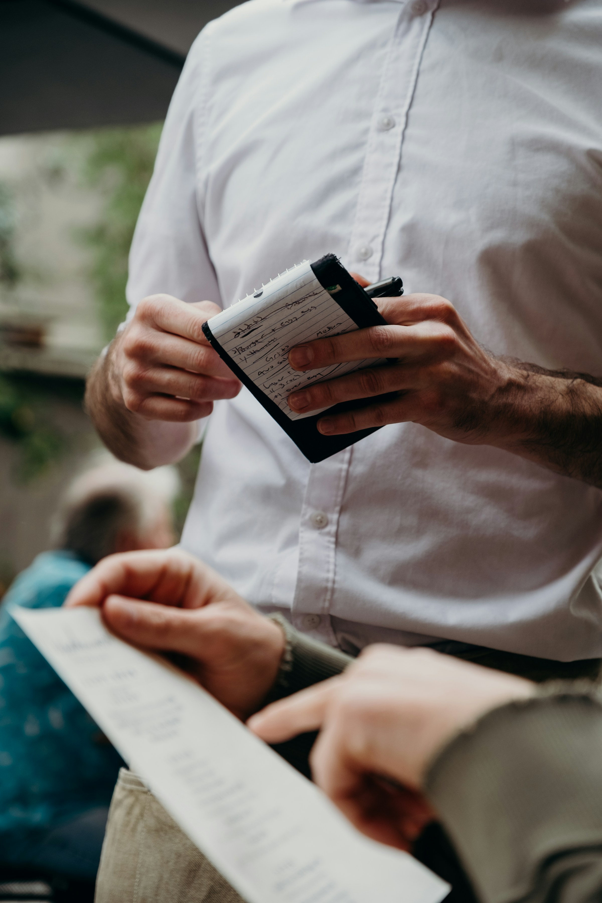 Un serveur dans un restaurant à côté d'un client qui examine l'addition | Source : Unsplash