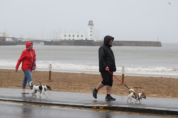 Des gens promènent leur chien sur le front de mer venteux de Scarborough, dans le North Yorkshire. | Photo : Getty Images