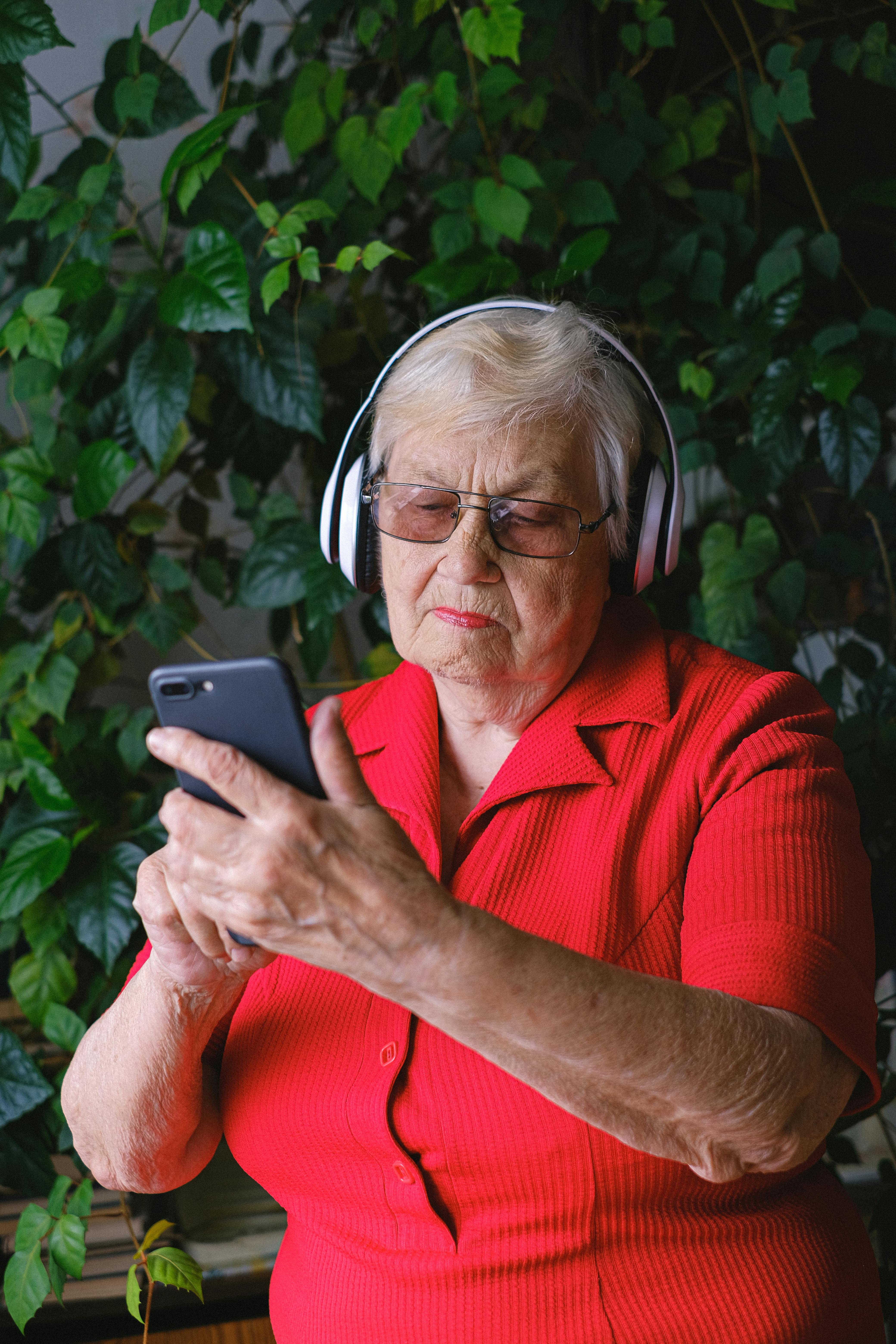 Une femme à l'air sérieuse utilisant un téléphone tout en portant des écouteurs | Source : Pexels