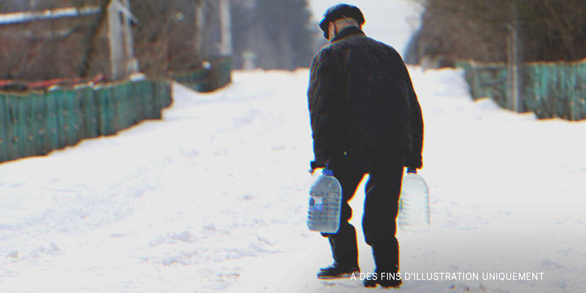Un homme âgé marchant dans la neige tout en transportant des bouteilles d'eau | Source : Shutterstock