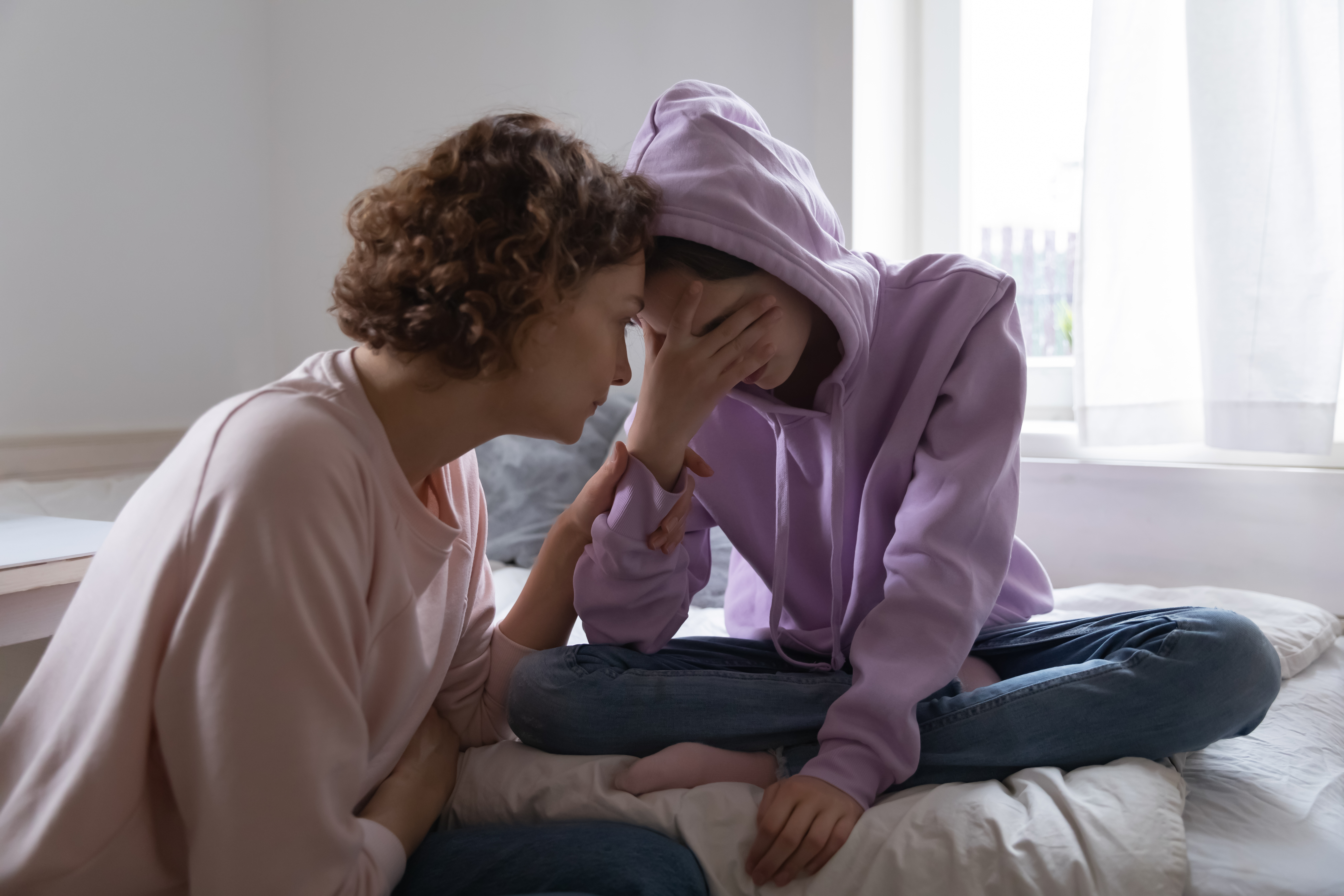 Une mère inquiète réconforte sa fille adolescente déprimée | Source : Shutterstock