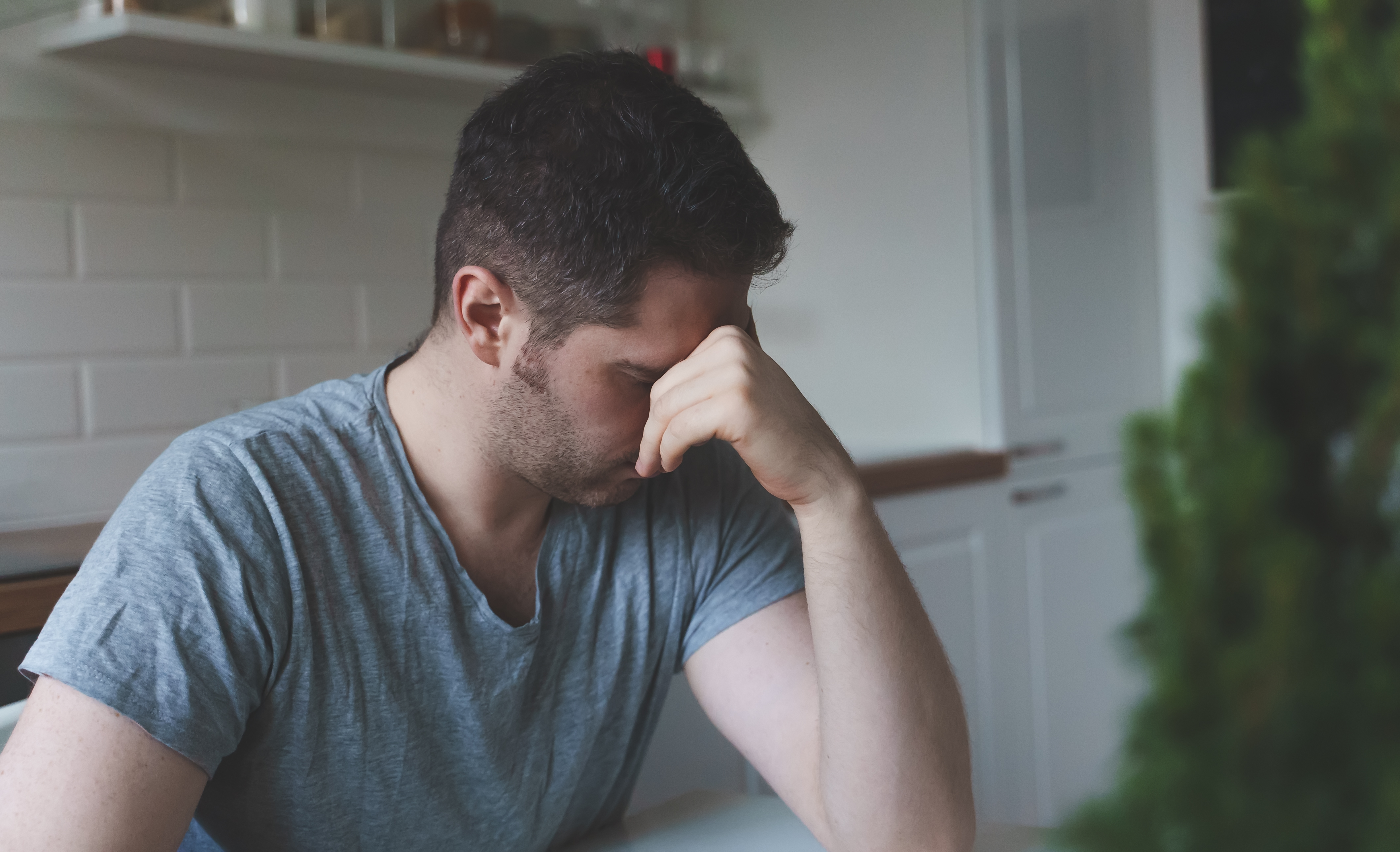 Un homme contrarié assis dans la cuisine | Source : Shutterstock