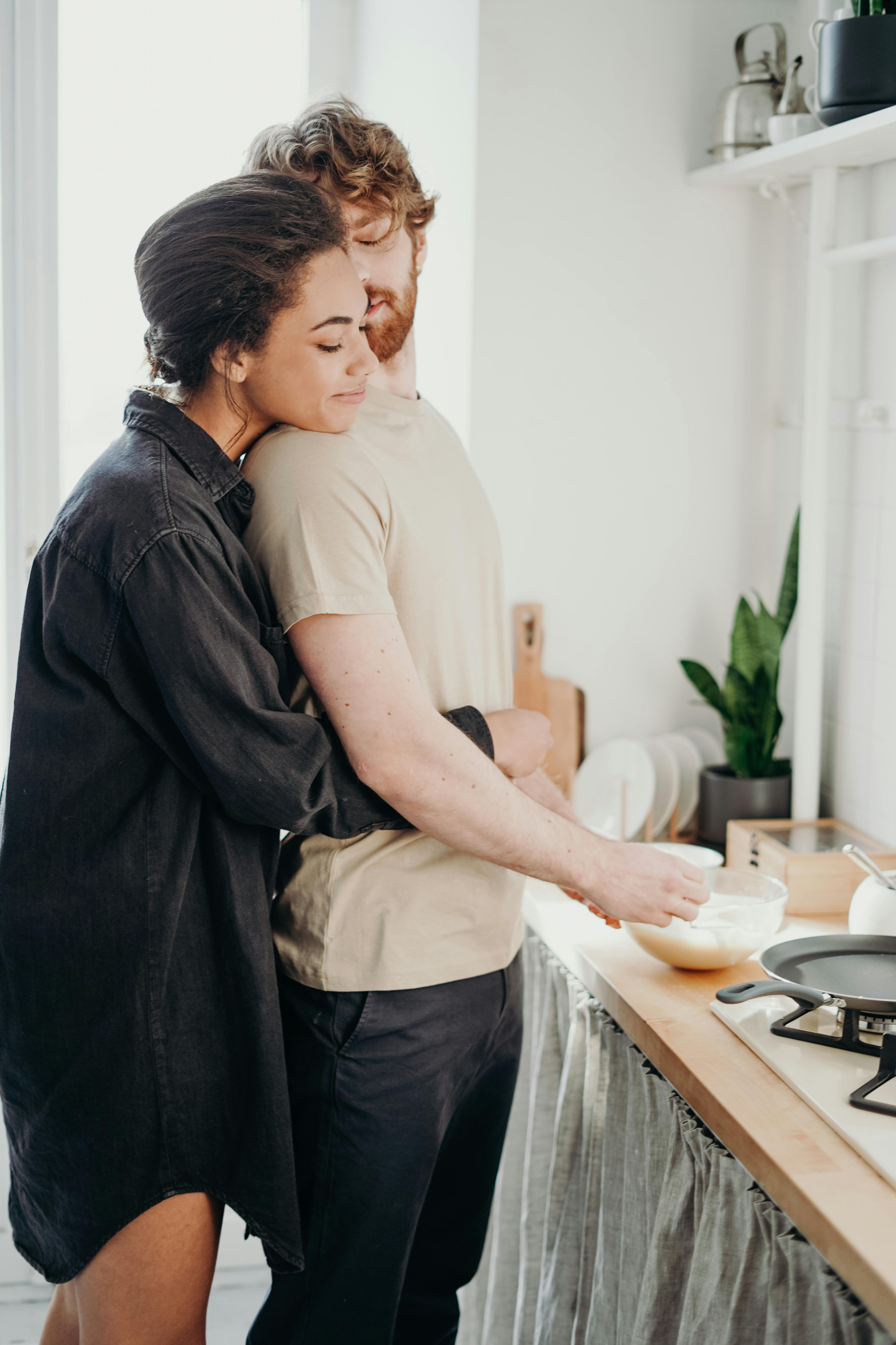 Un couple s'embrassant pendant que l'homme prépare un repas | Source : Pexels