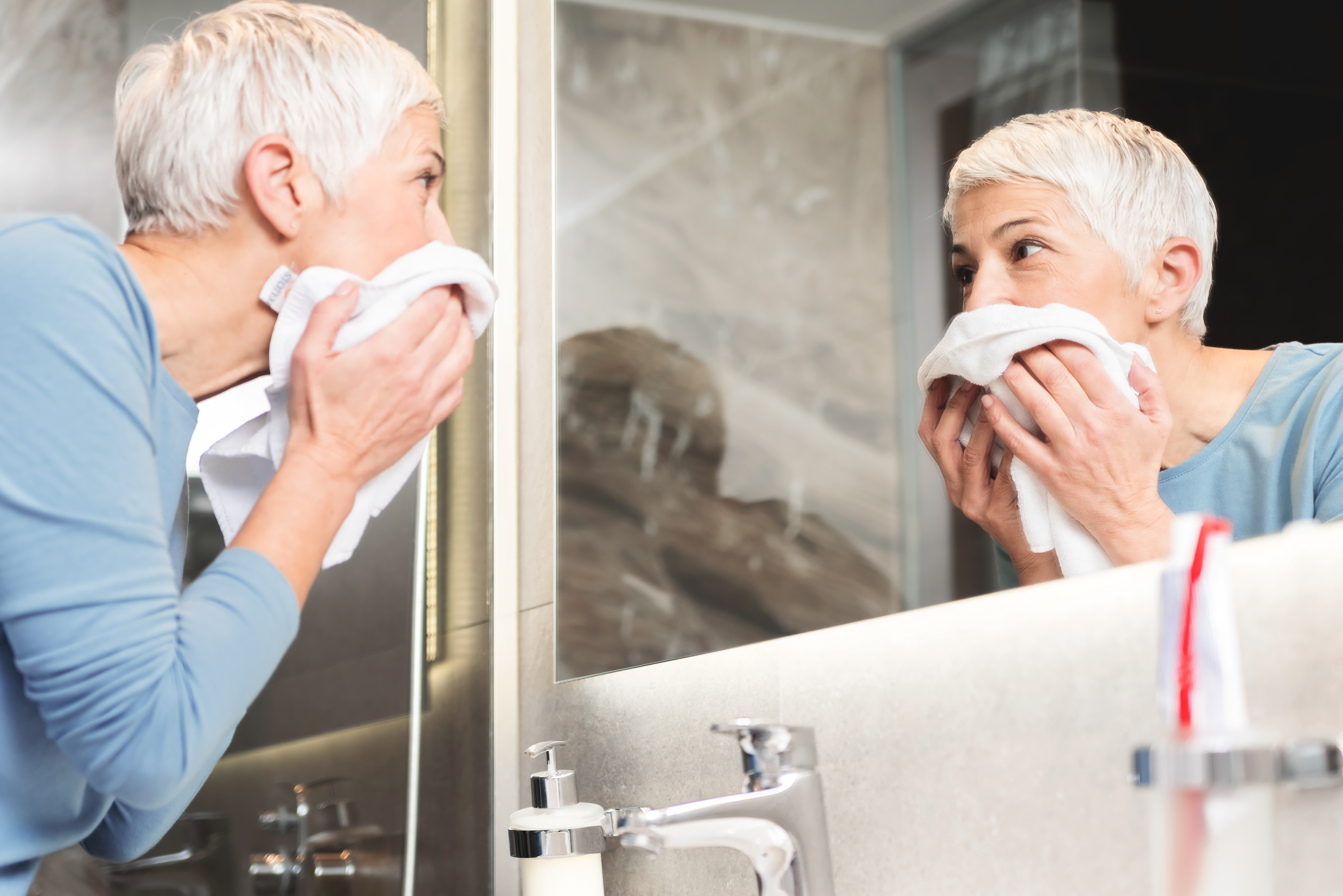 Une emme aux cheveux gris et courts s'essuyant le visage | Source : Shutterstock