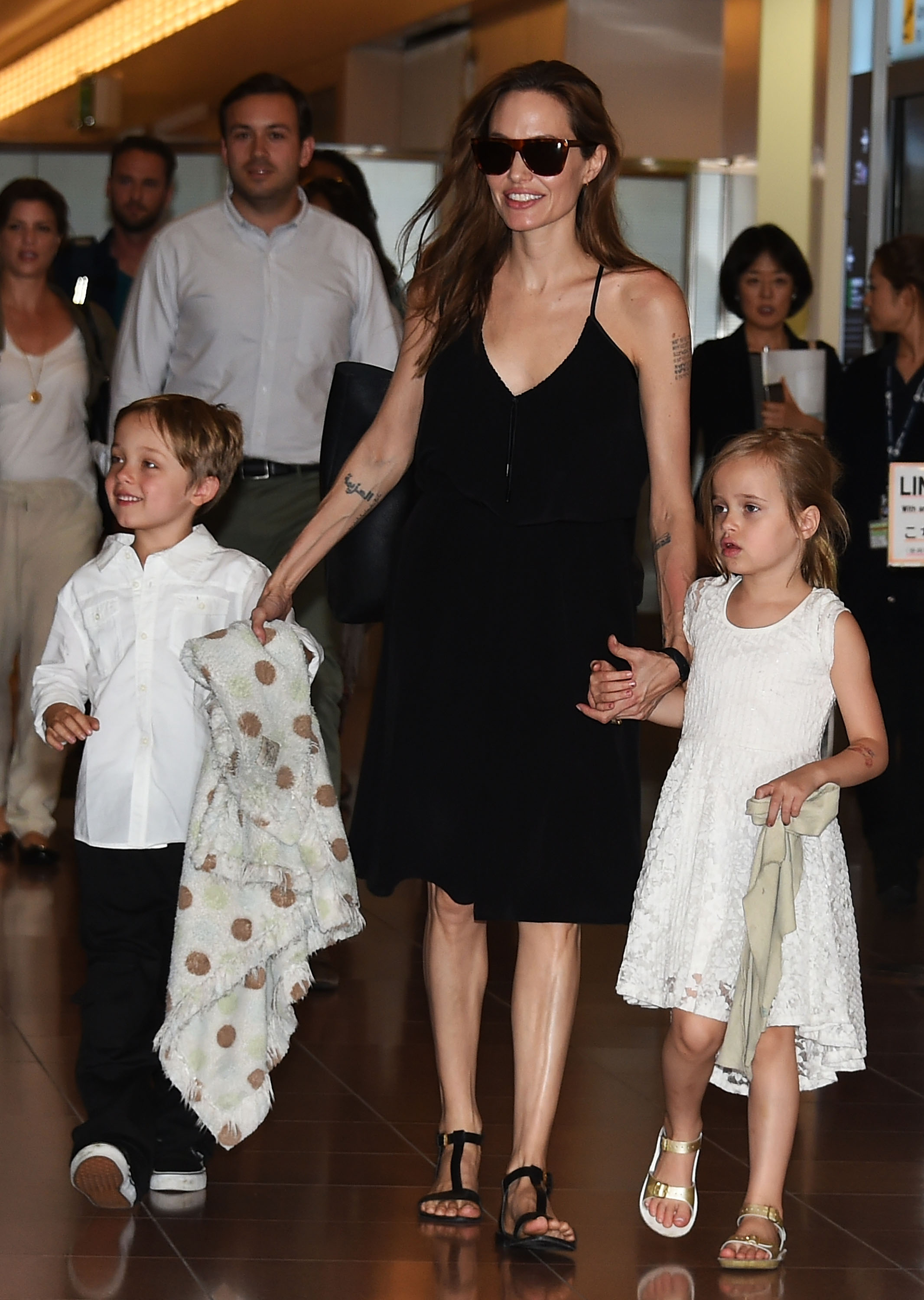 Knox Jolie-Pitt avec sa mère et sa sœur jumelle à l'aéroport de Haneda, le 21 juin 2014, à Tokyo, au Japon. | Source : Getty Images