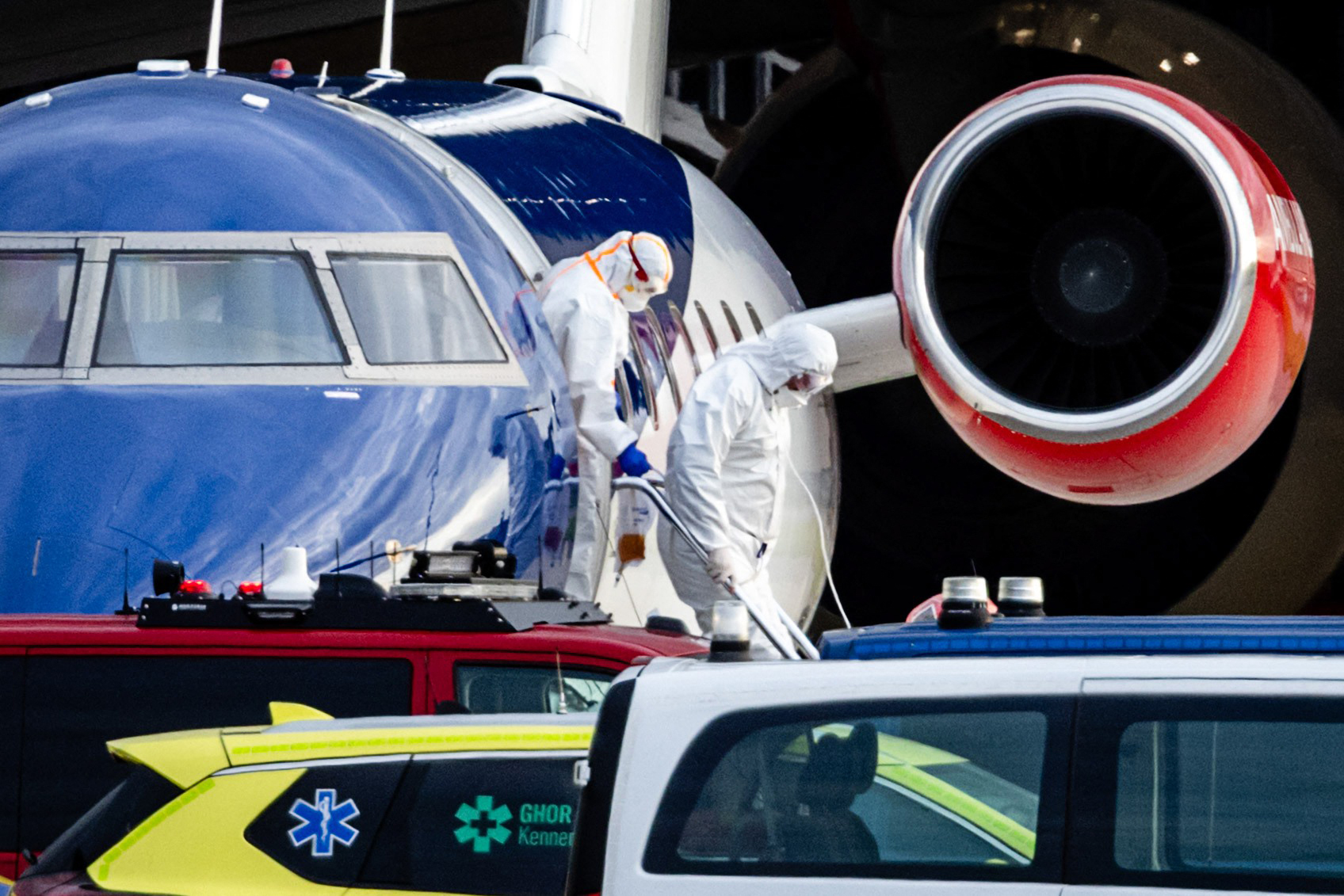 Deux personnes en combinaison de protection descendant d'un avion médical Bombardier Challenger 605 qui aurait transporté certains des passagers du paquebot MV Hondius, soupçonnés d'être infectés par le hantavirus, à l'aéroport de Schiphol à Amsterdam, le 6 mai 2026 I Source : Getty Images