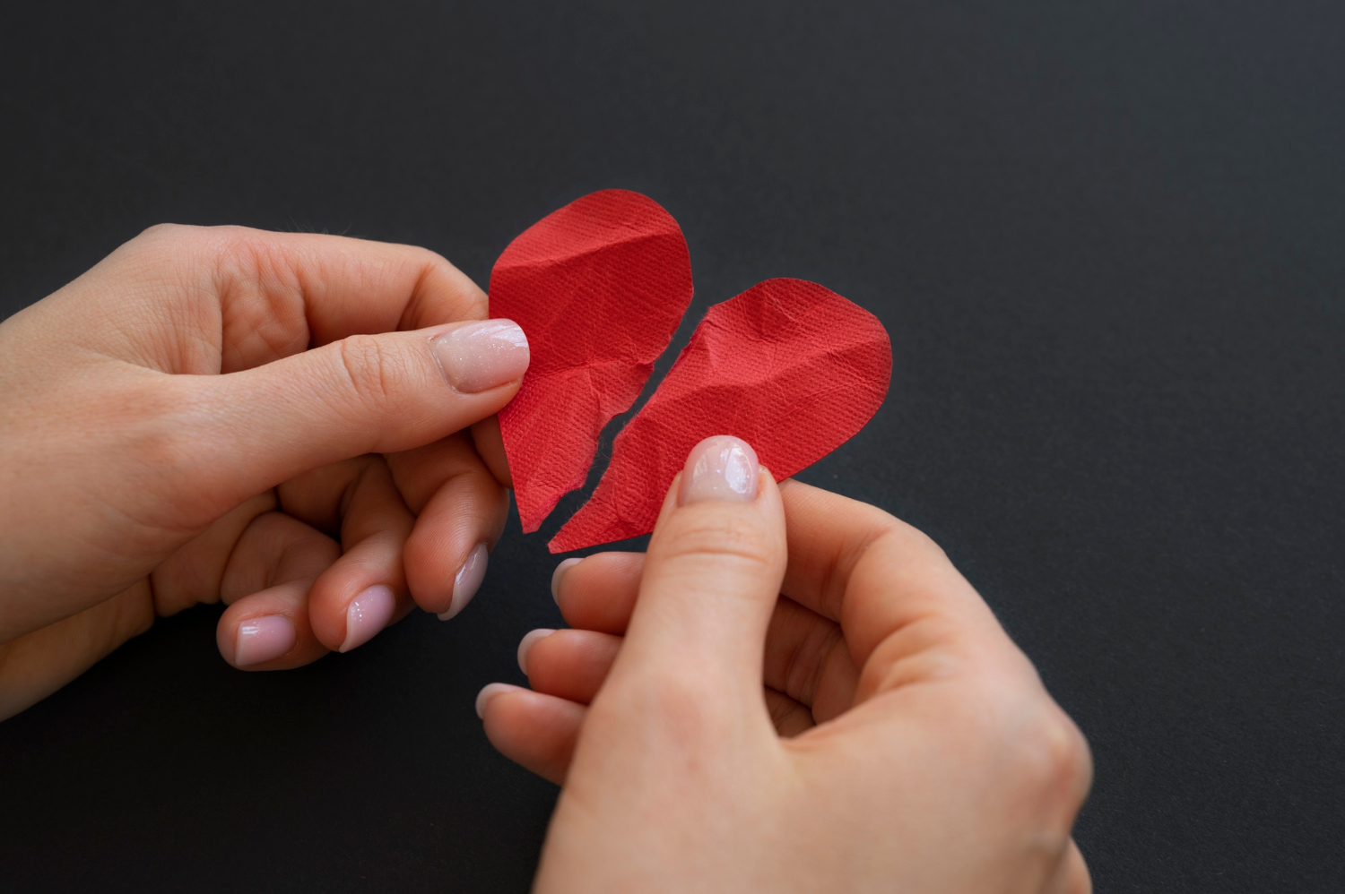 Une femme tenant un cœur en papier brisé | Source : Freepik
