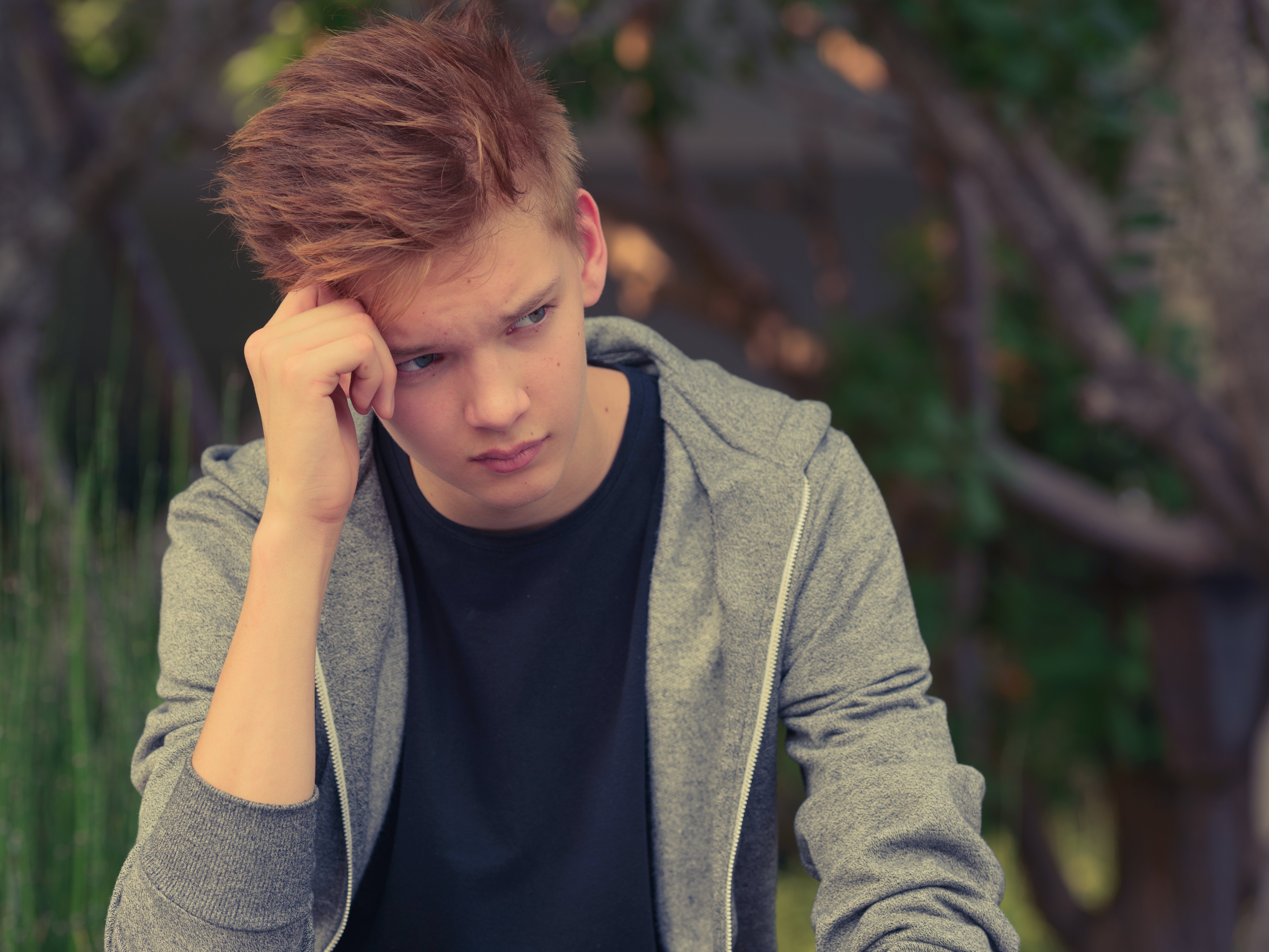 Un adolescent contrarié assis avec sa main contre sa tête | Source : Shutterstock