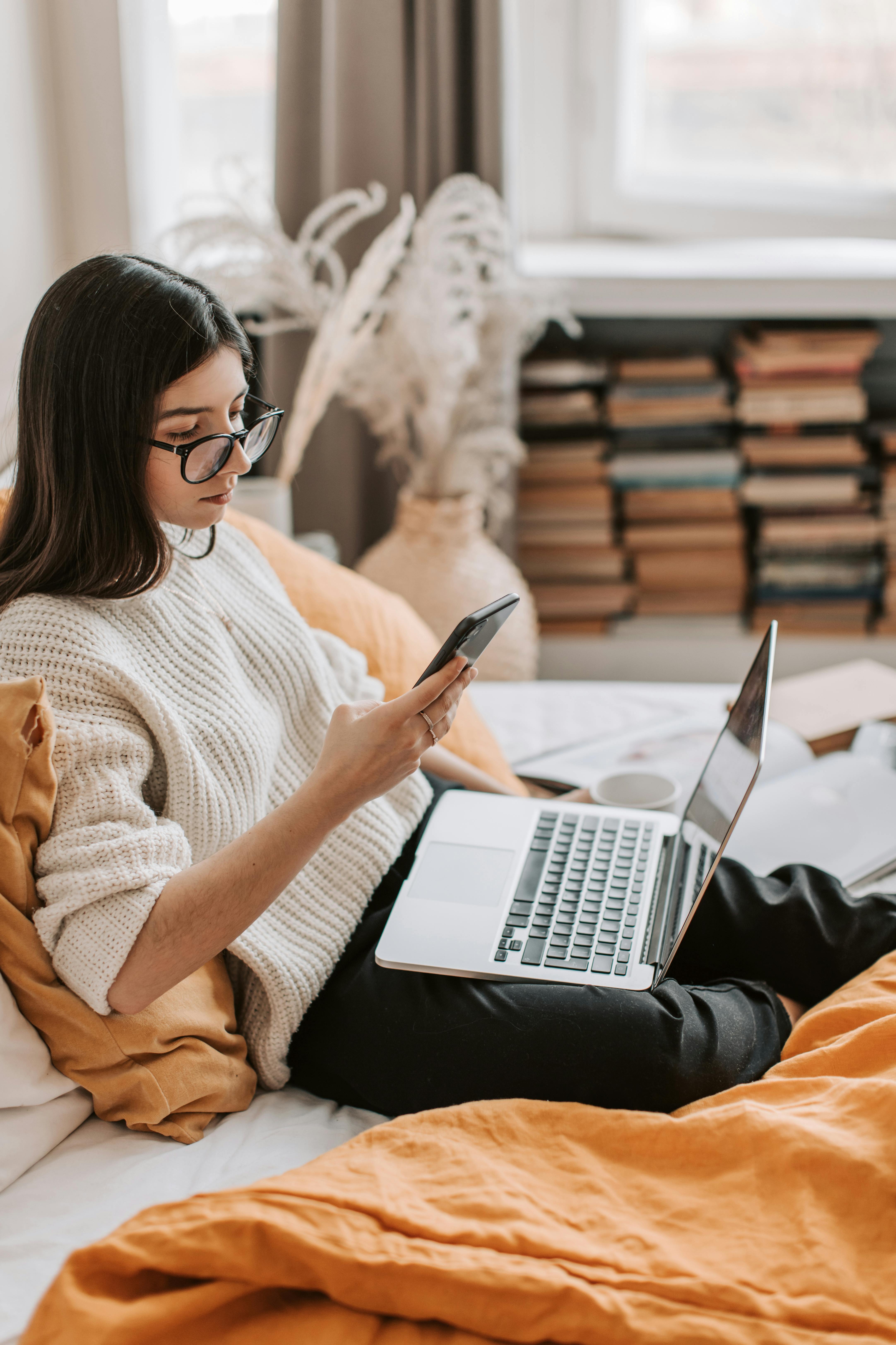 Une femme assise dans son lit et utilisant son téléphone | Source : Pexels