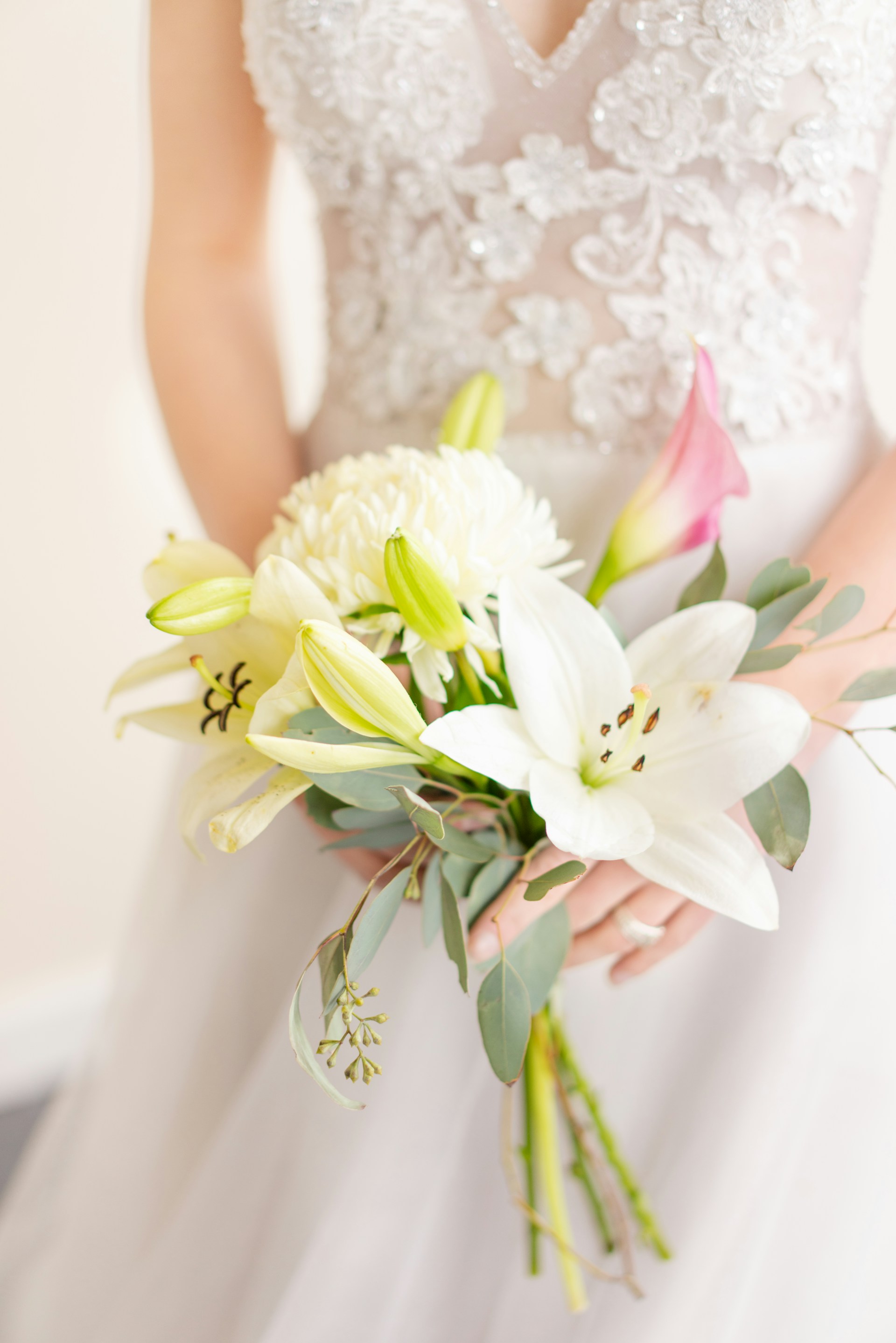 Gros plan d'une mariée tenant un bouquet de lys | Source : Unsplash