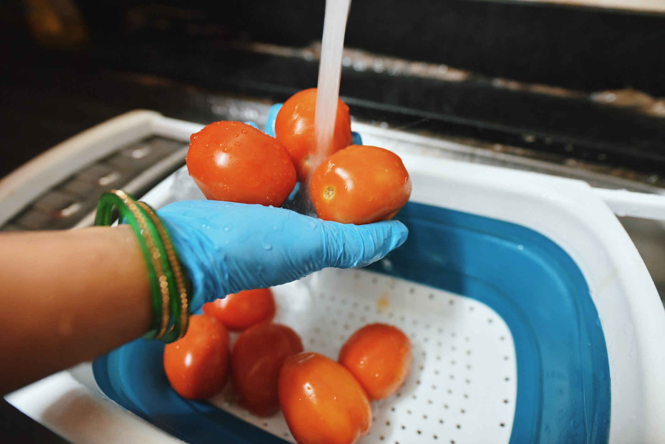 Une femme lavant des tomates à l'évier de la cuisine. | Photo : Getty Images