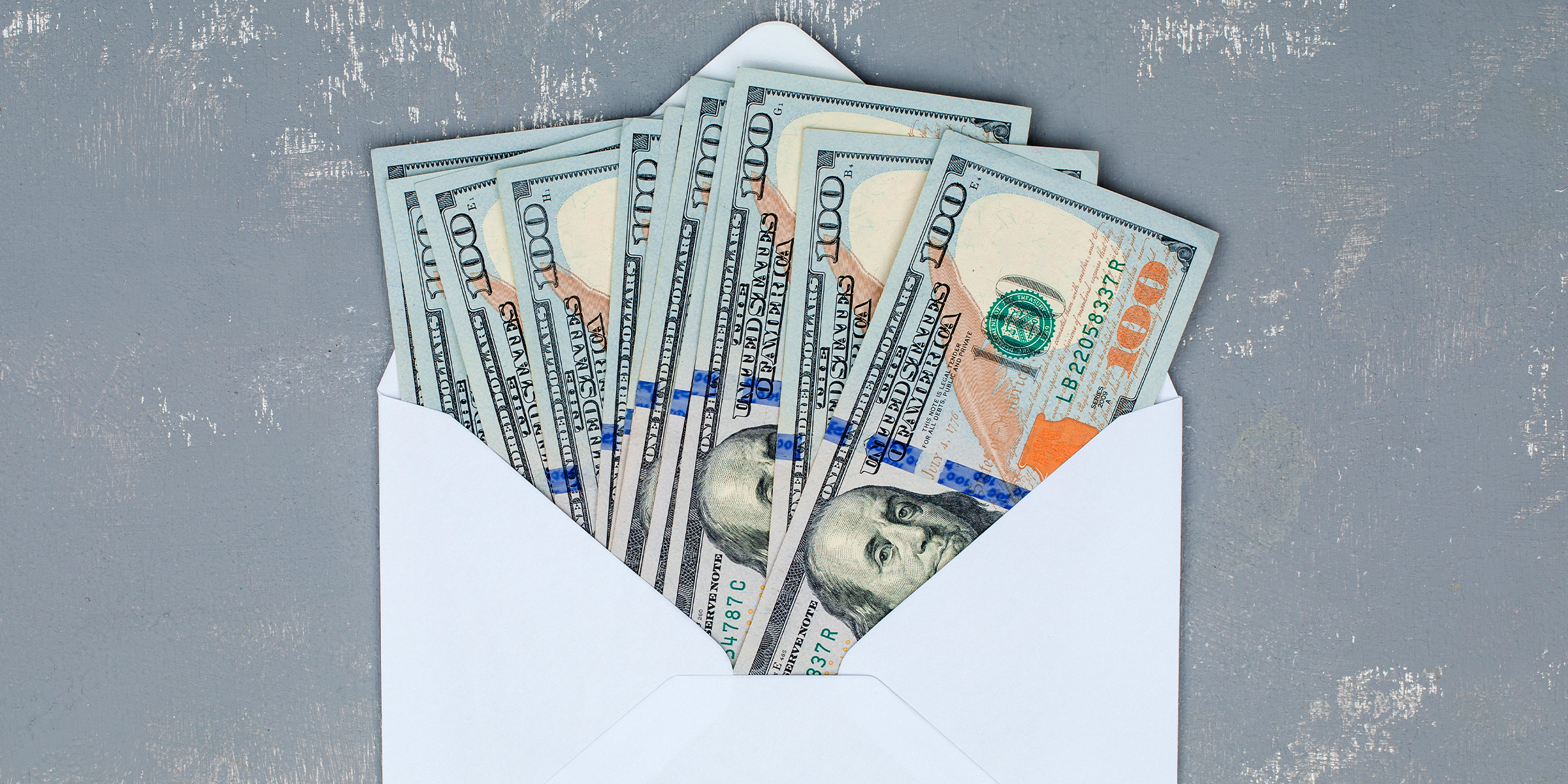 Une enveloppe blanche ouverte remplie de billets de 100 $ | Source : Shutterstock