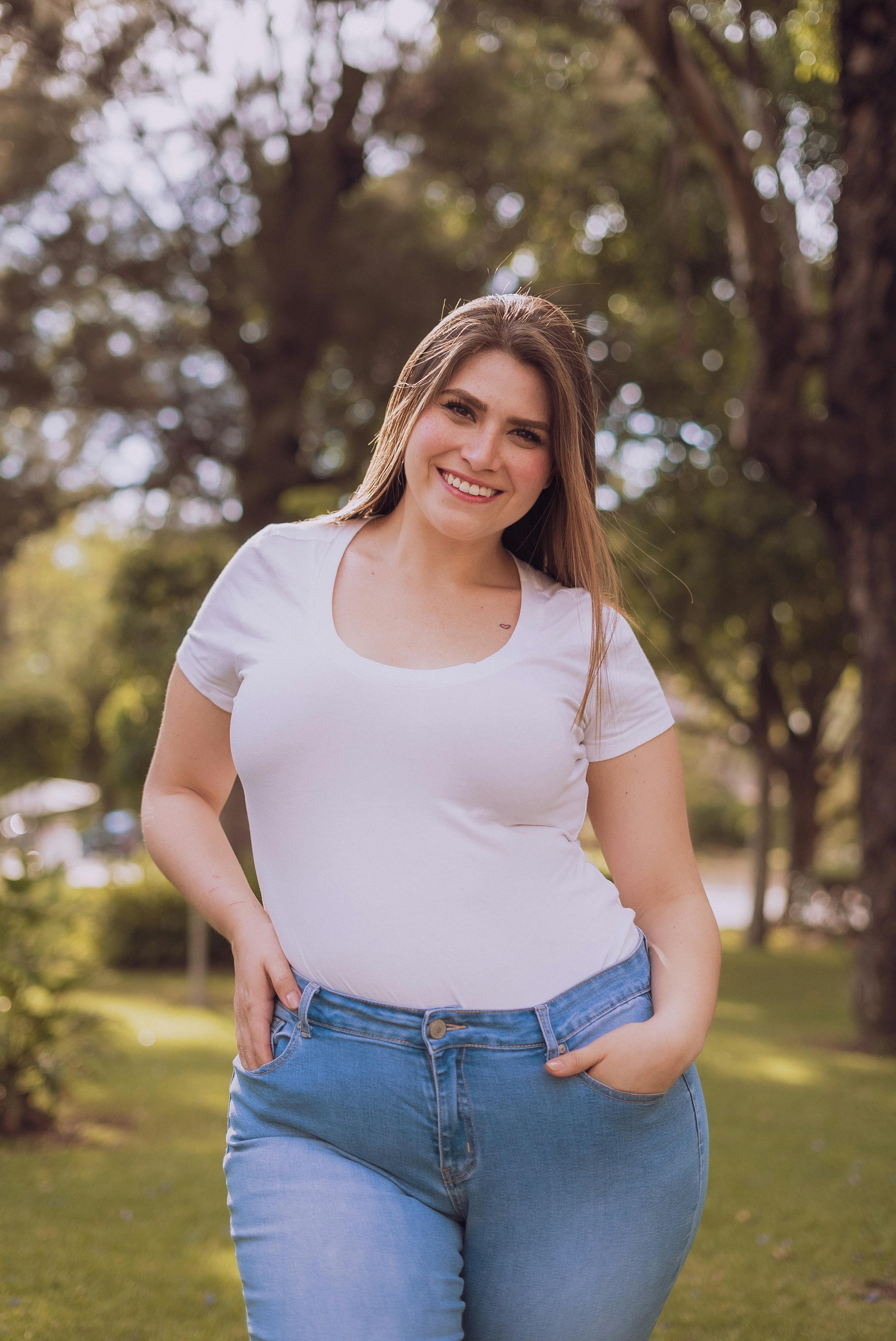 Une femme souriante vêtue d'un haut blanc et d'un jean | Source : Pexels