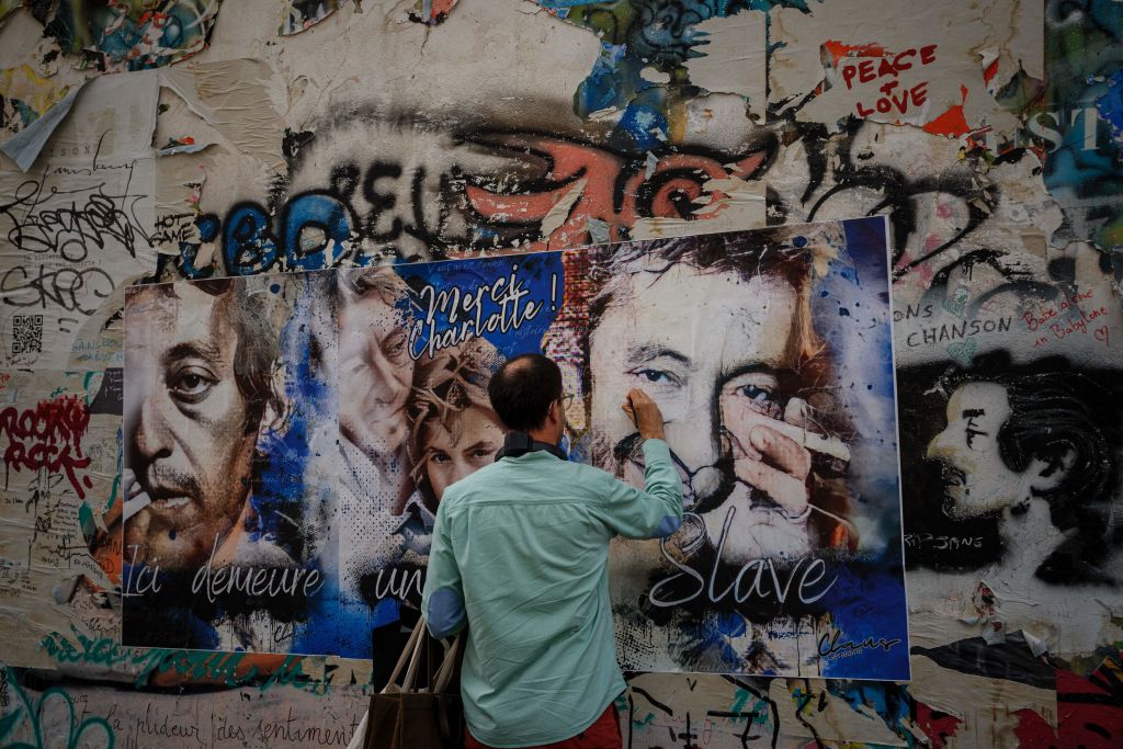 Un visiteur écrit sur une affiche accrochée au mur devant la « Maison Gainsbourg », la demeure du chanteur, compositeur et acteur français Serge Gainsbourg, le jour de son ouverture au public à Paris, le 20 septembre 2023 I Source : Getty Images