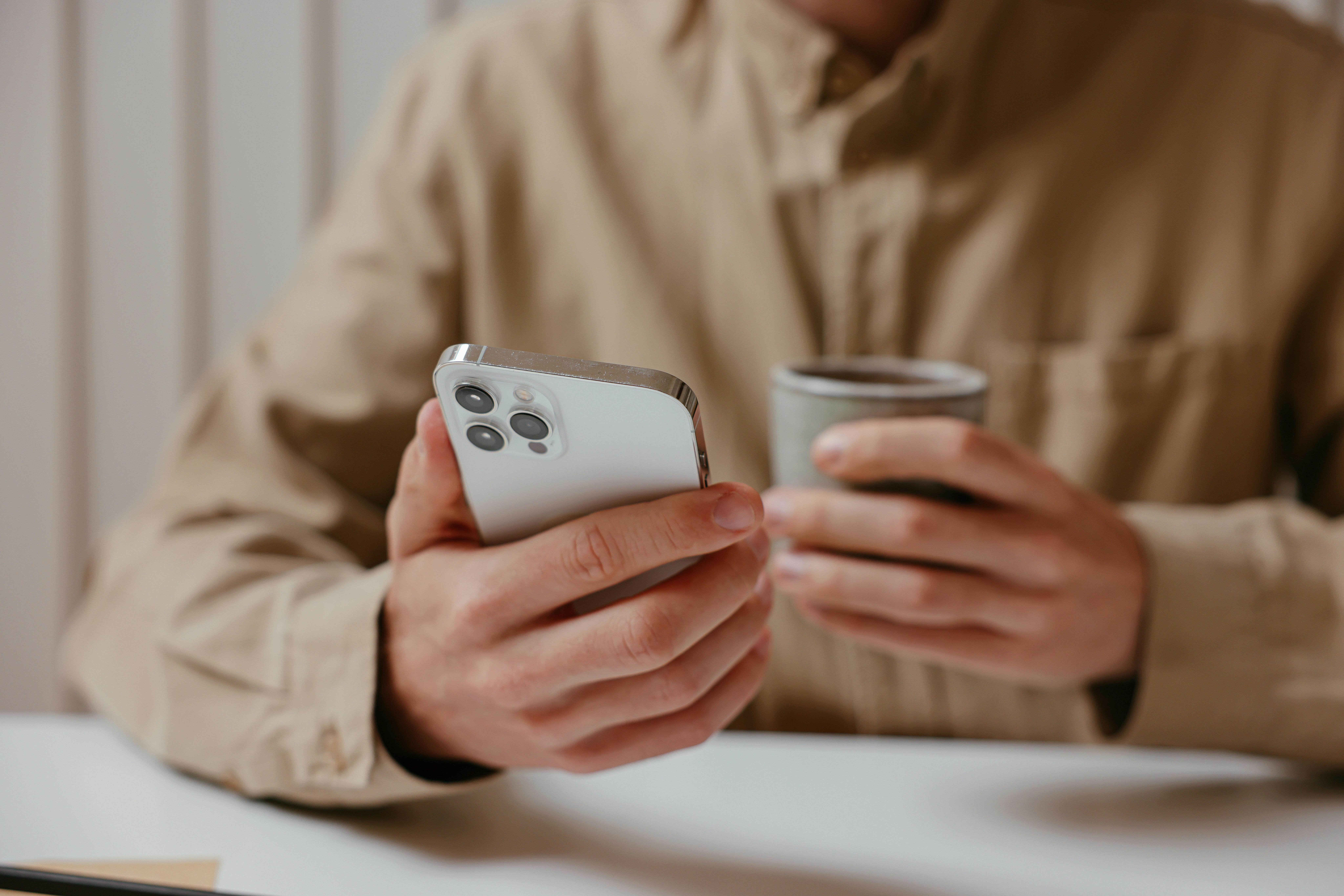 Un homme tenant un téléphone et une tasse de café | Source : Pexels