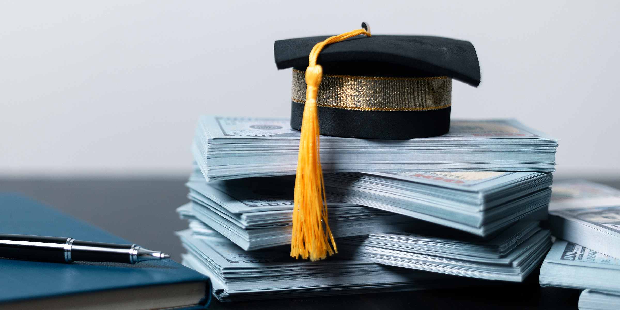 Une casquette de fin d'études posée sur des piles d'argent liquide | Source : Shutterstock