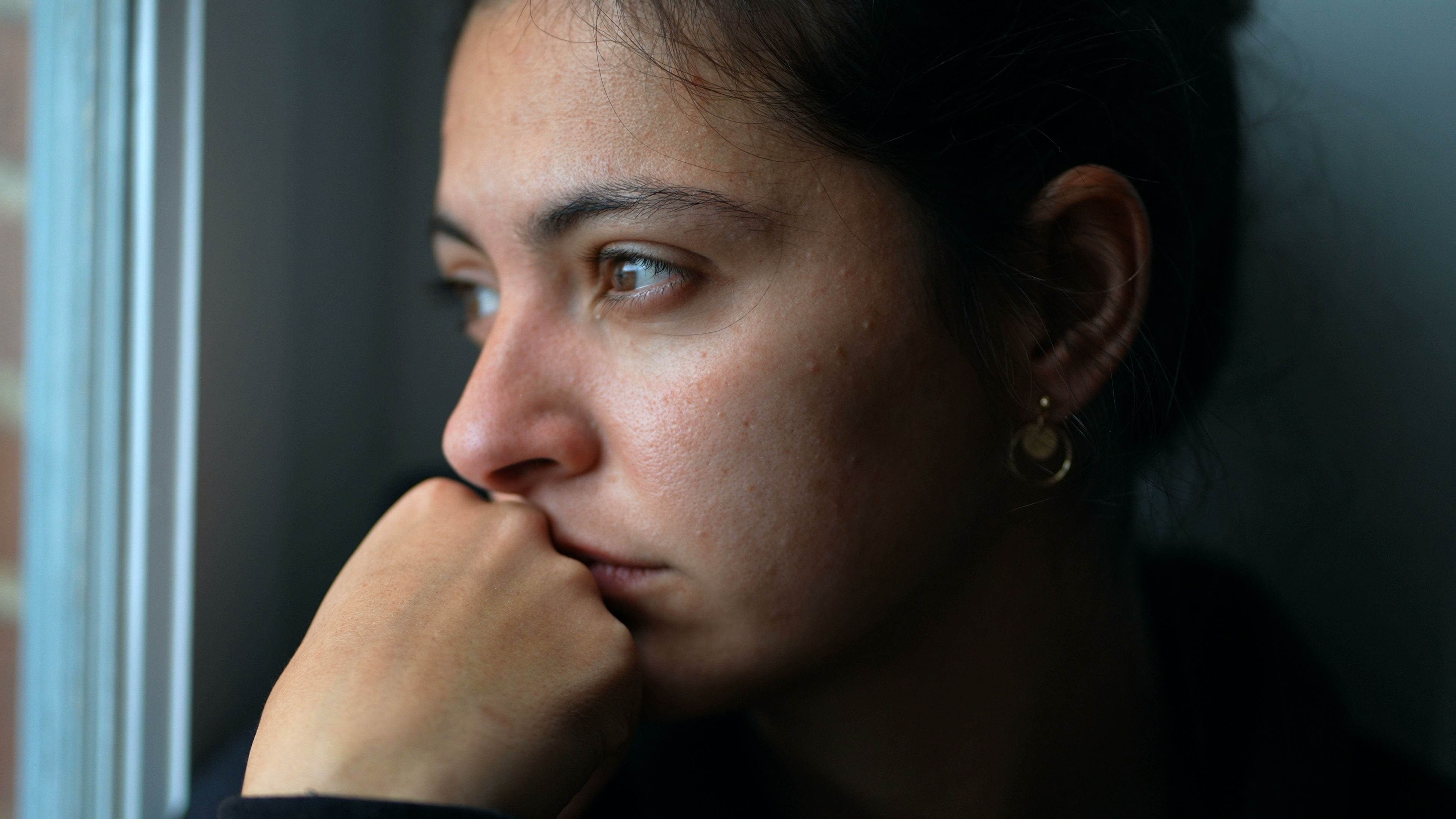 Une jeune femme perdue dans ses pensées qui regarde par la fenêtre | Source : Shutterstock