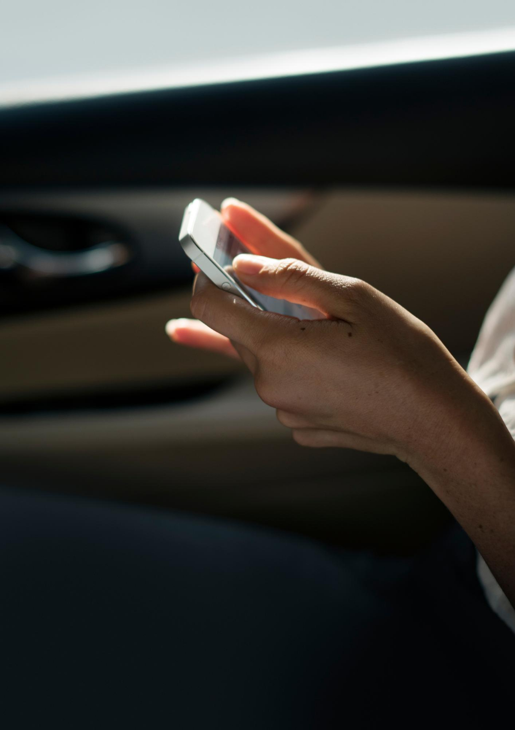 Une femme tenant son téléphone alors qu'elle est assise dans une voiture. | Source : Freepik