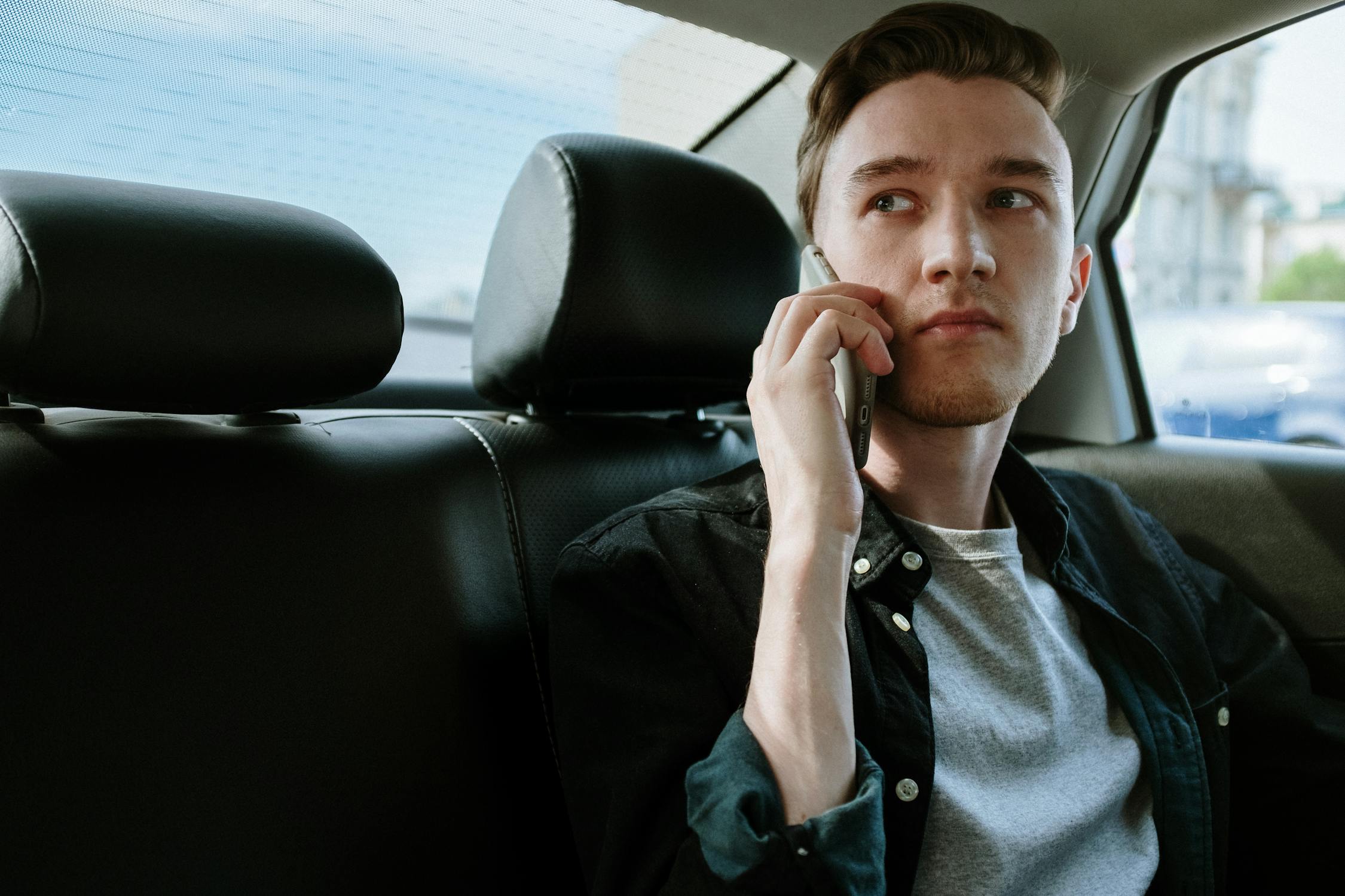 Un homme sérieux sur son téléphone dans sa voiture | Source : Pexels