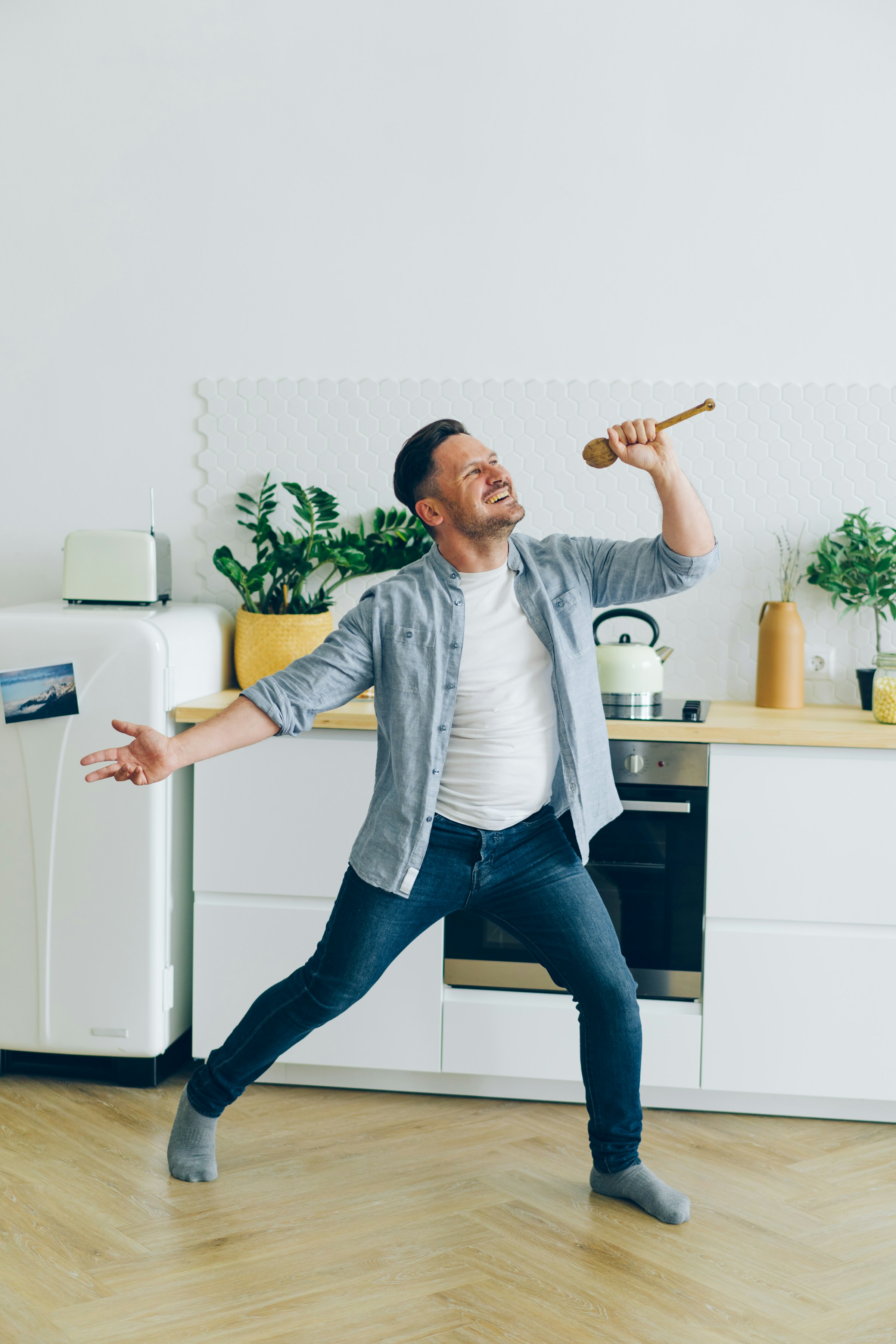 Un homme s'amusant dans la cuisine en tenant une cuillère en bois | Source : Unsplash