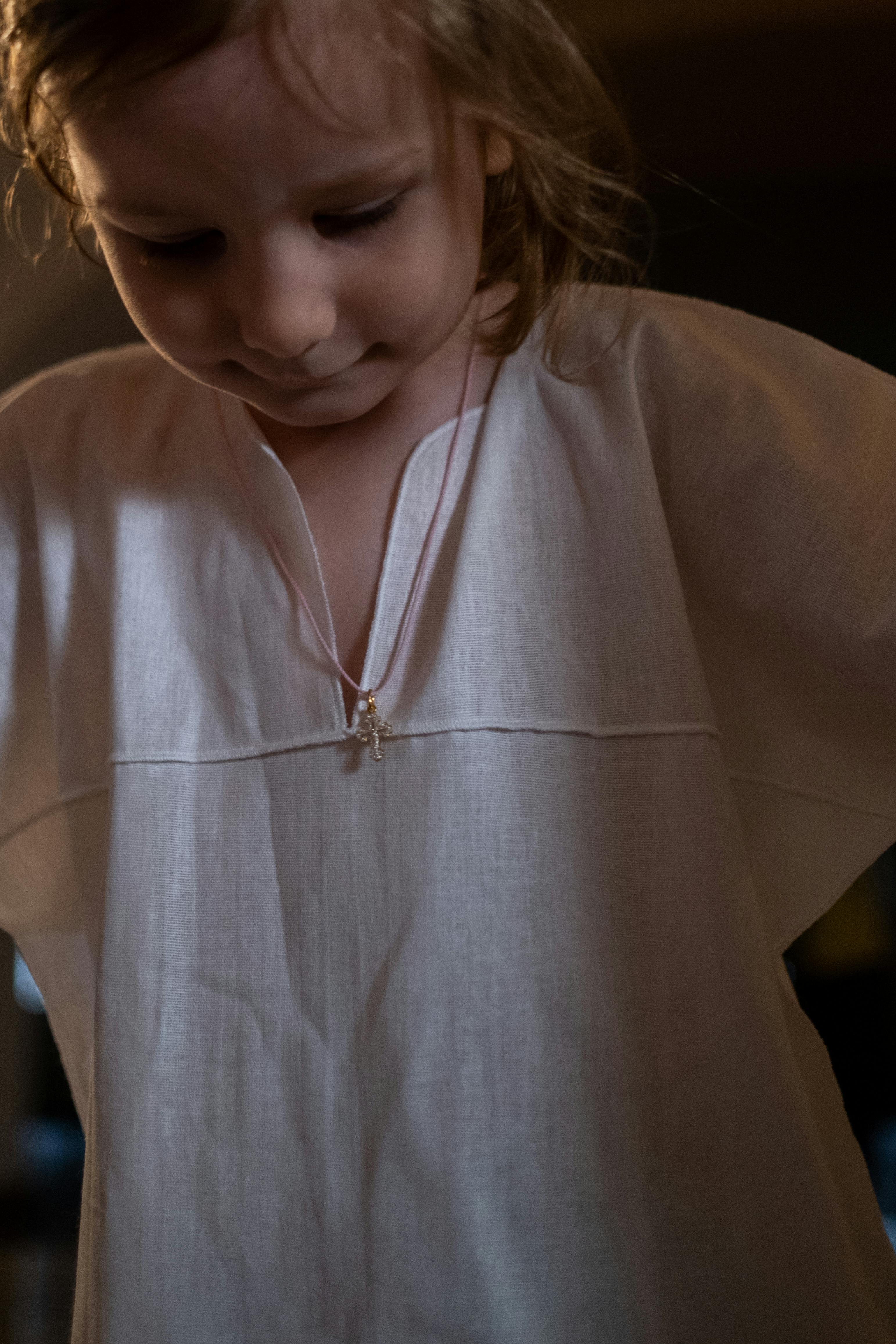 Une petite fille en robe blanche qui regarde vers le bas | Source : Pexels