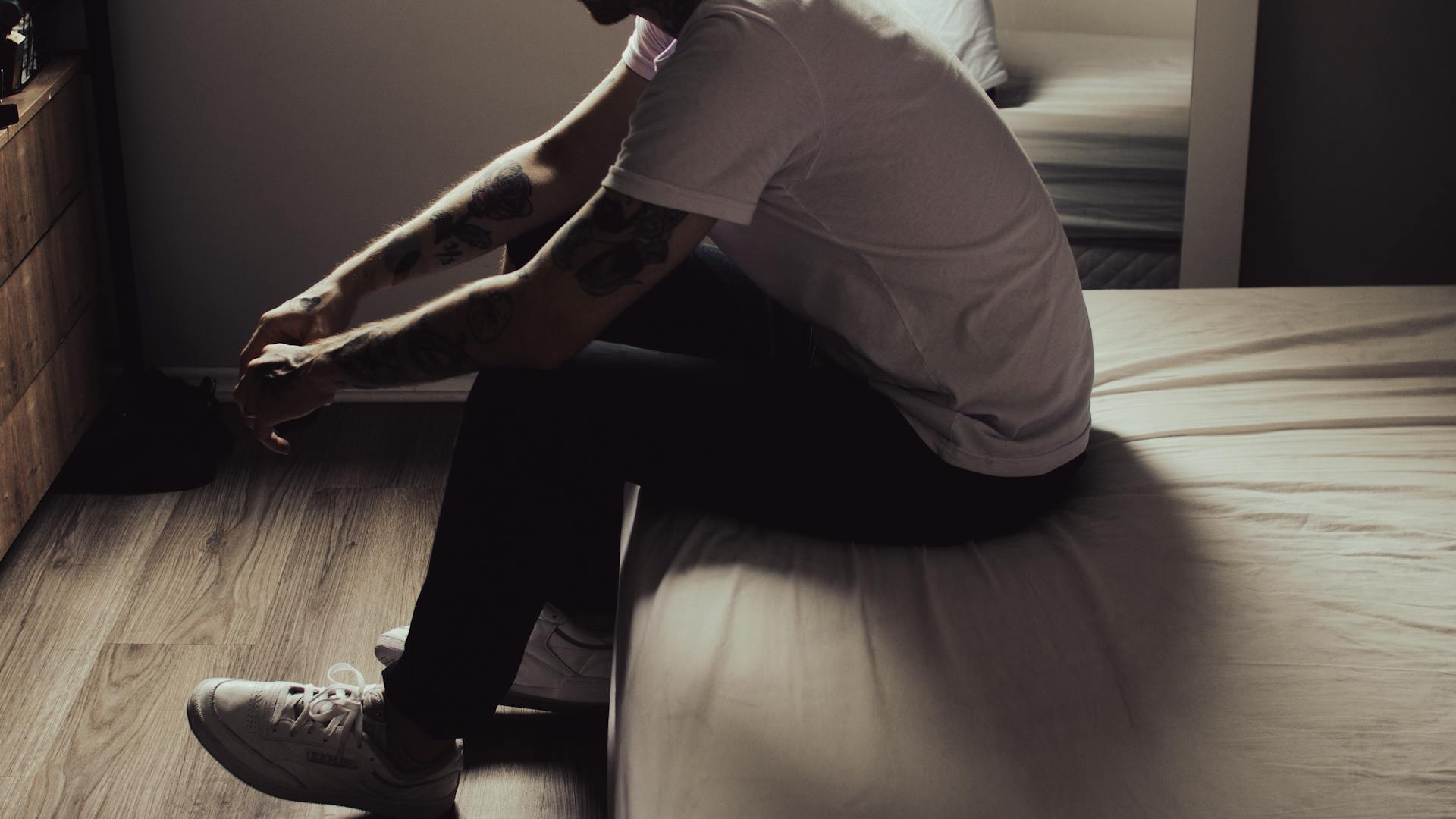 Un gros plan d'un homme assis sur le coin du lit | Source : Pexels