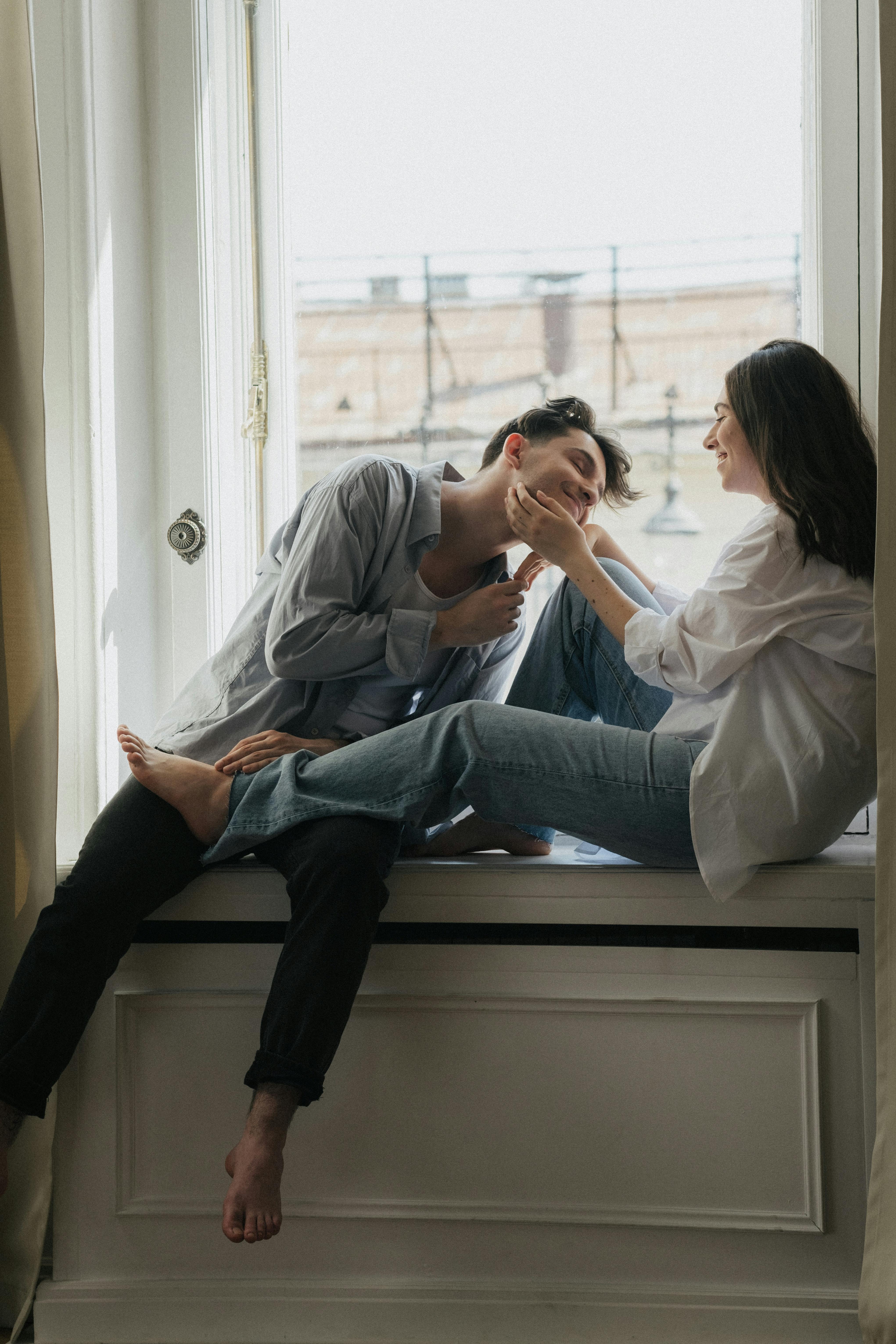 Un couple heureux qui traîne sur un rebord de fenêtre | Source : Pexels