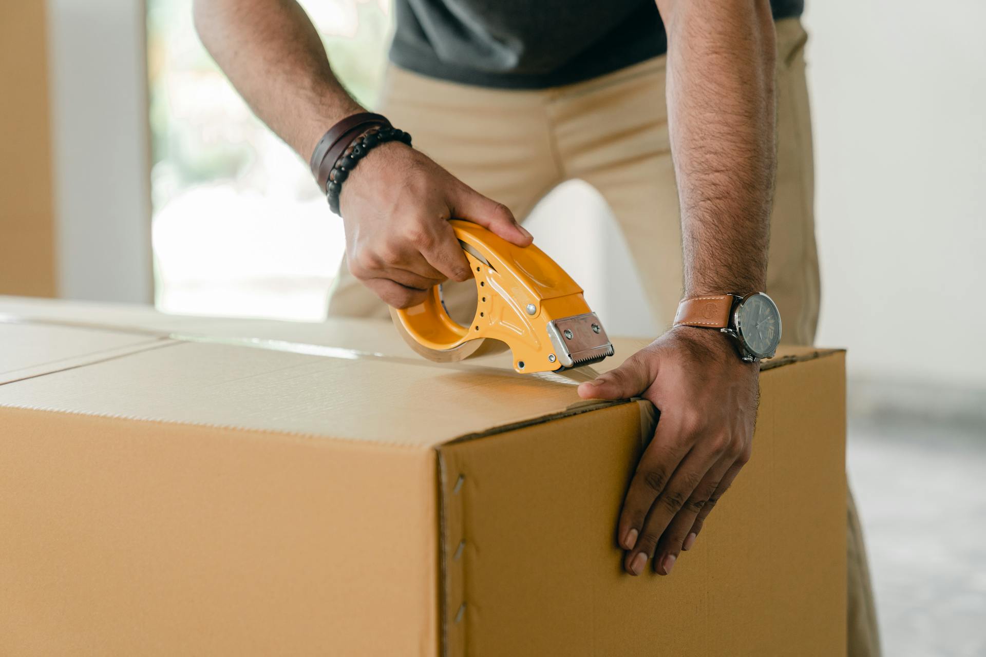 Un homme emballe des vêtements dans une boîte | Source : Pexels