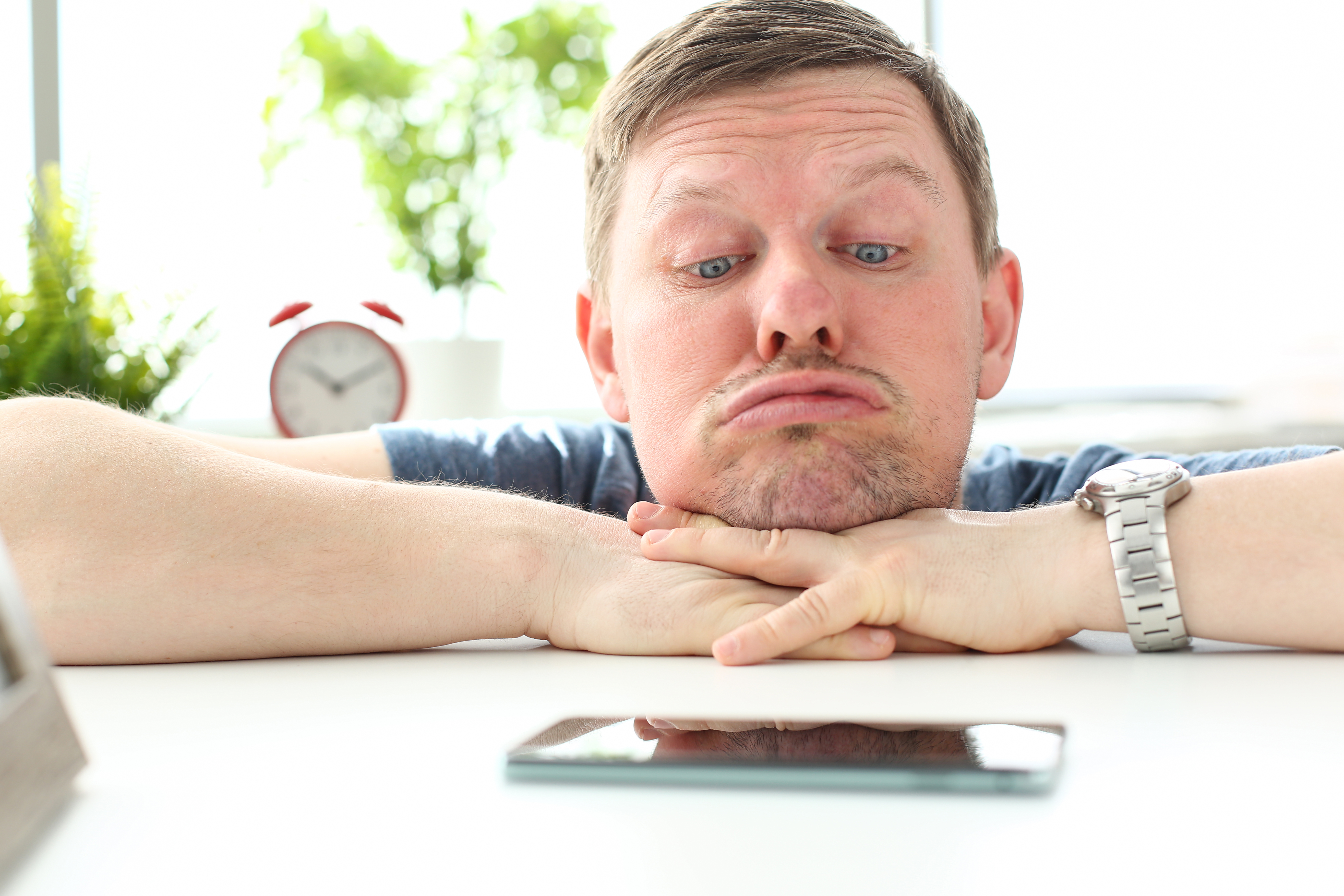 Un homme qui fixe son téléphone en attendant un message. | Source : Getty Images